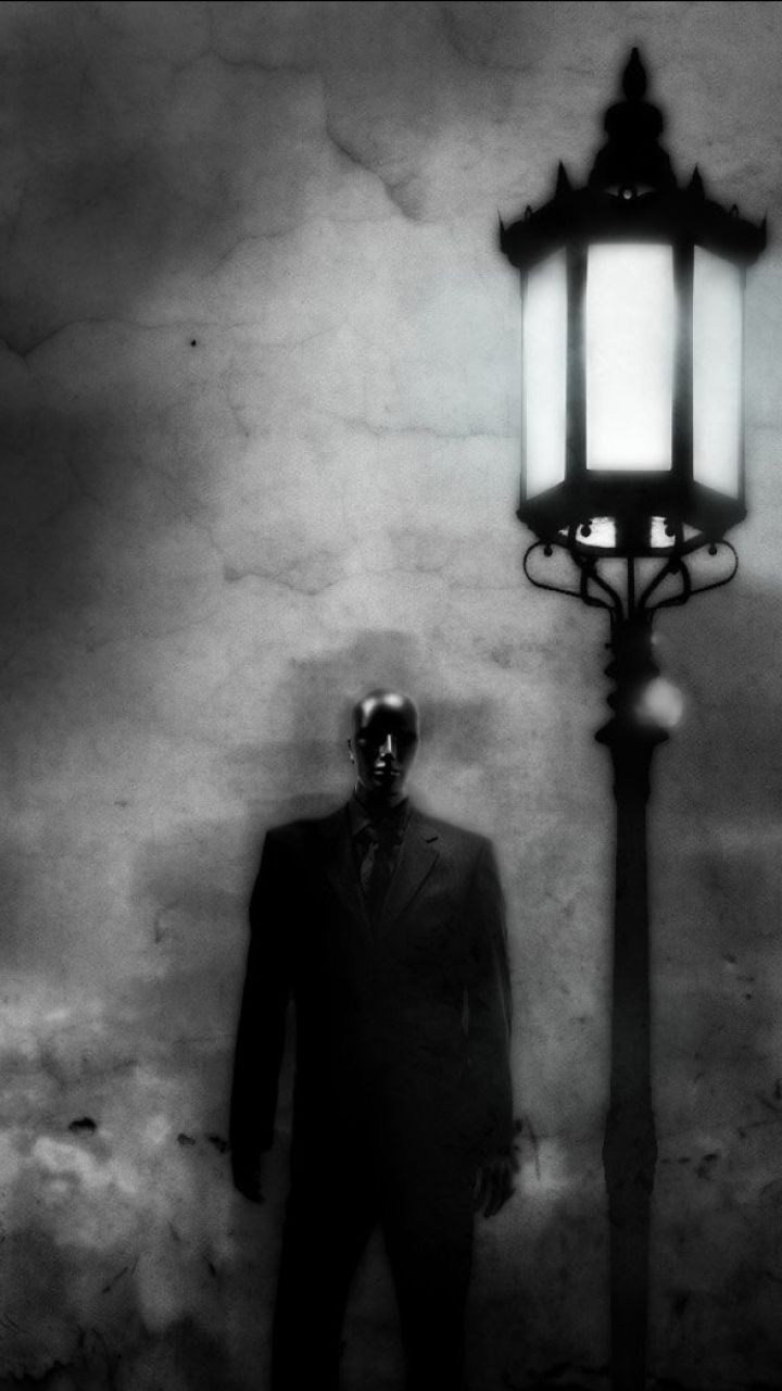 A suited figure stands in front of a street lamp - Creepy, horror