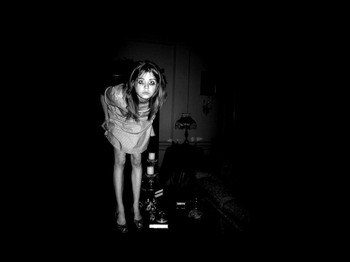 A girl stands in a dark room, holding a light. - Creepy