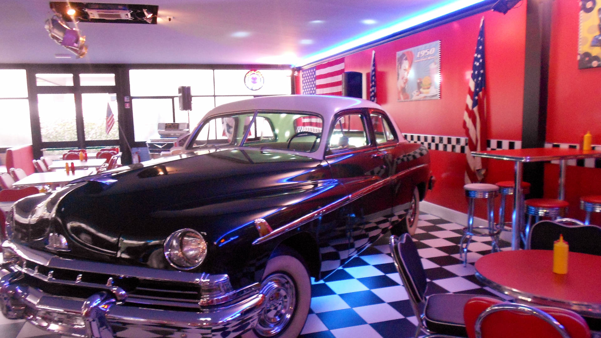 Classic car in a red and black room with a black and white checkered floor. - 50s