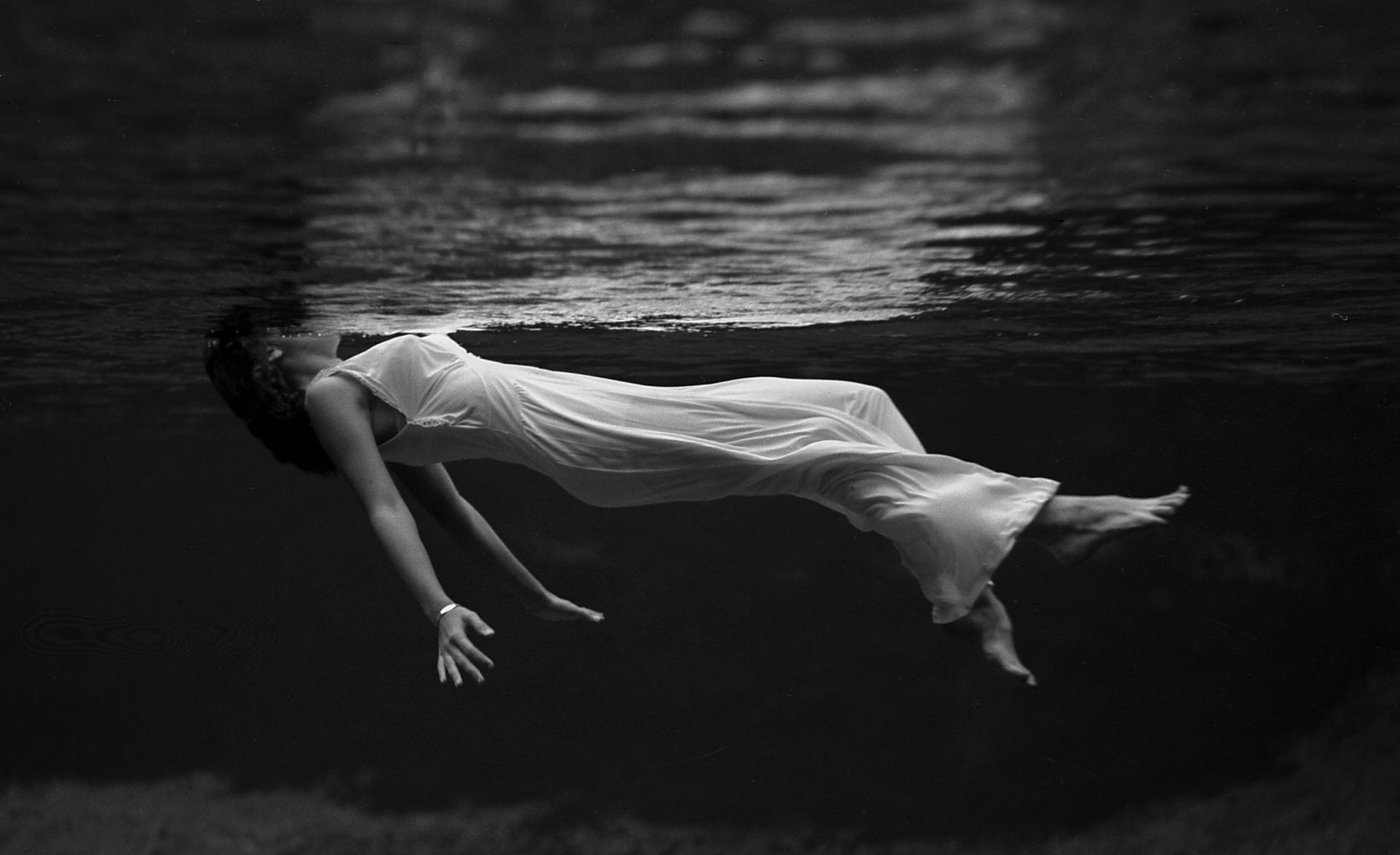 A woman in white is floating under water - Creepy