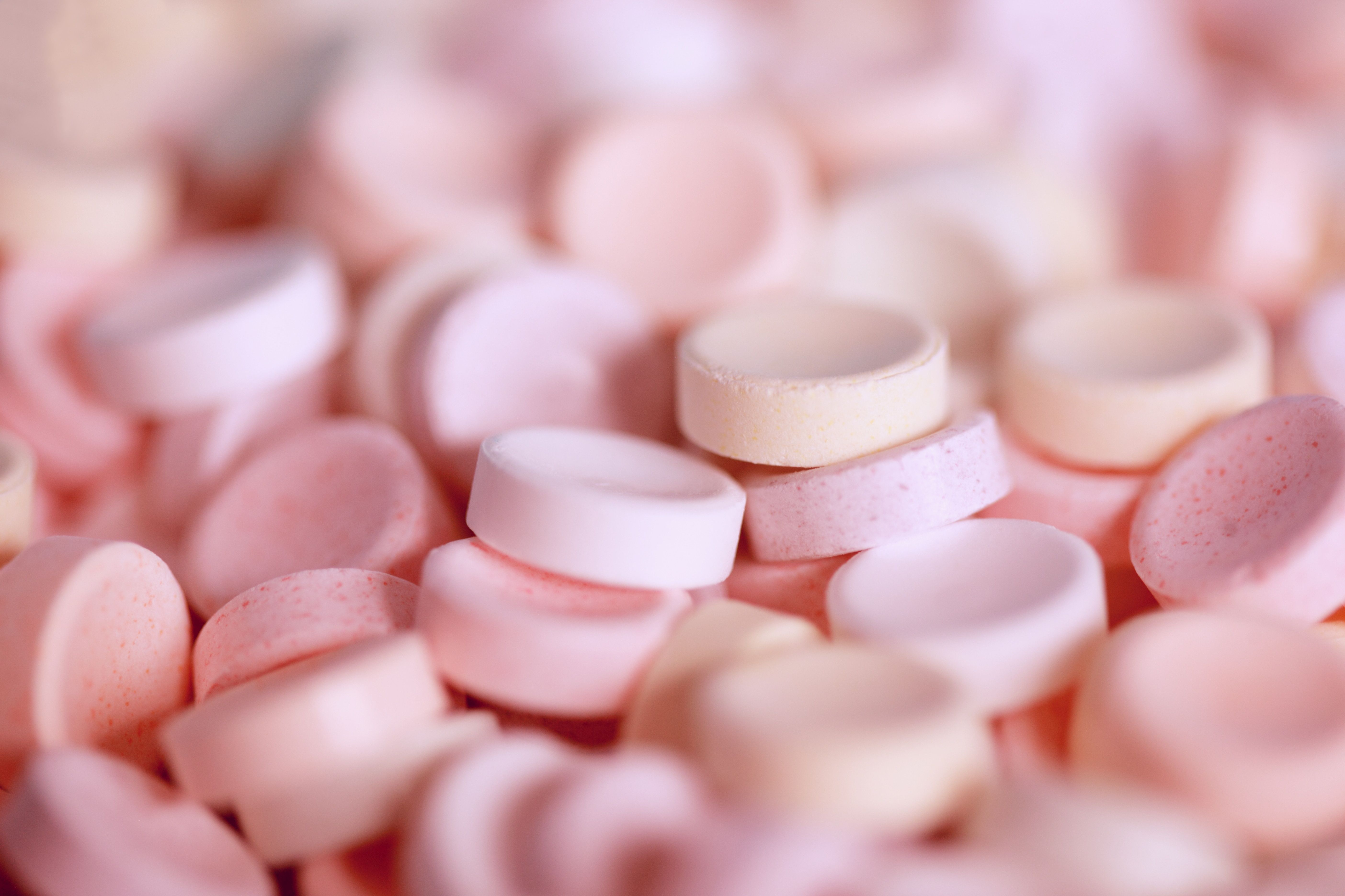 A pile of pink and white round tablets - 
