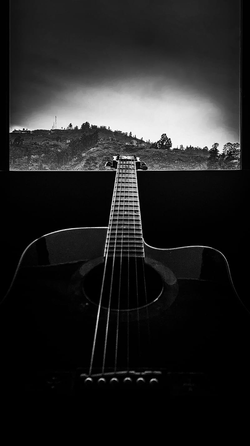 A guitar is sitting in front of an open window - Guitar