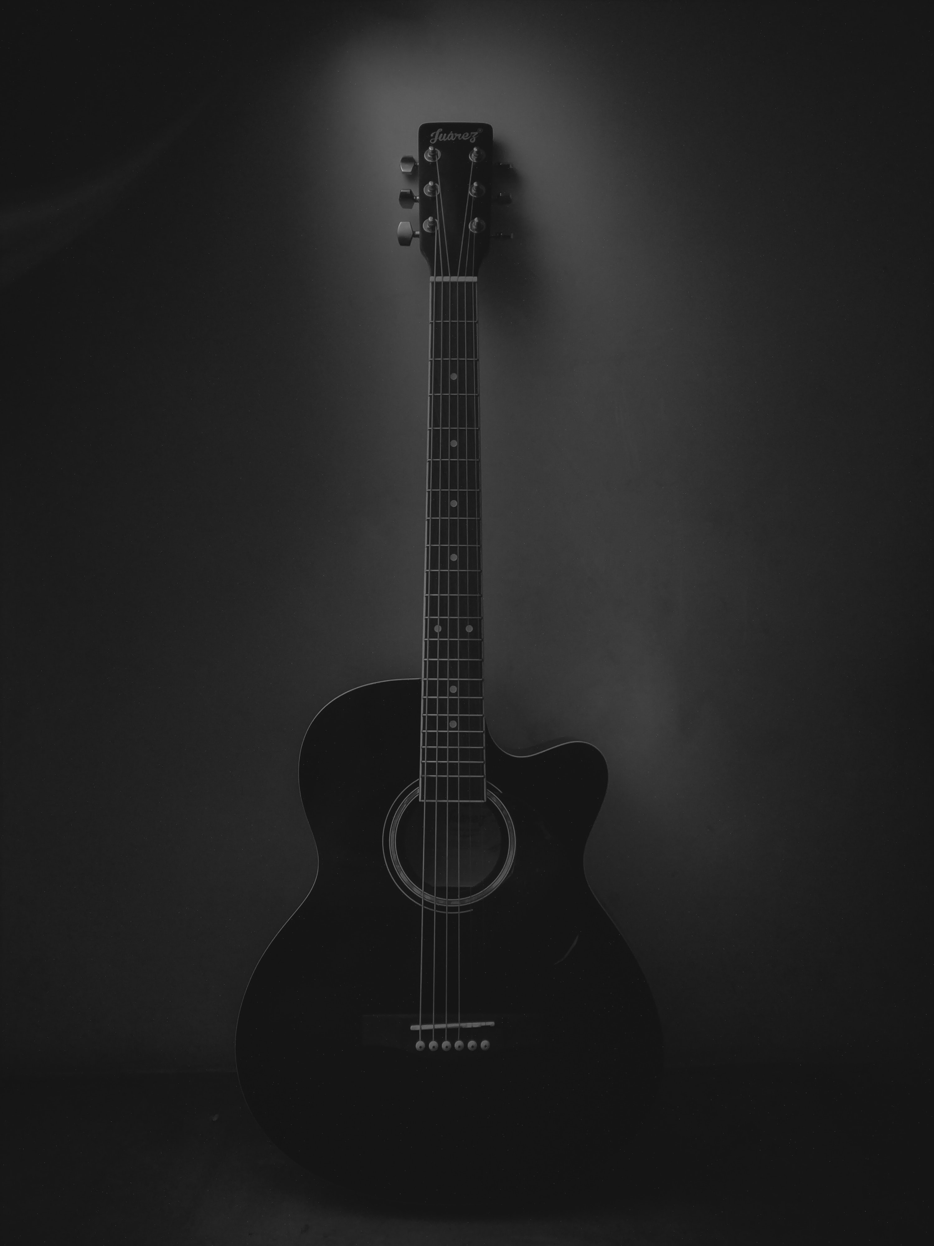 A black guitar against a black background. - Guitar