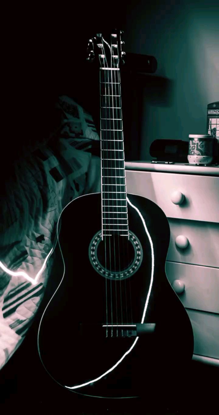 A black and white photo of a guitar on a bed. - Guitar