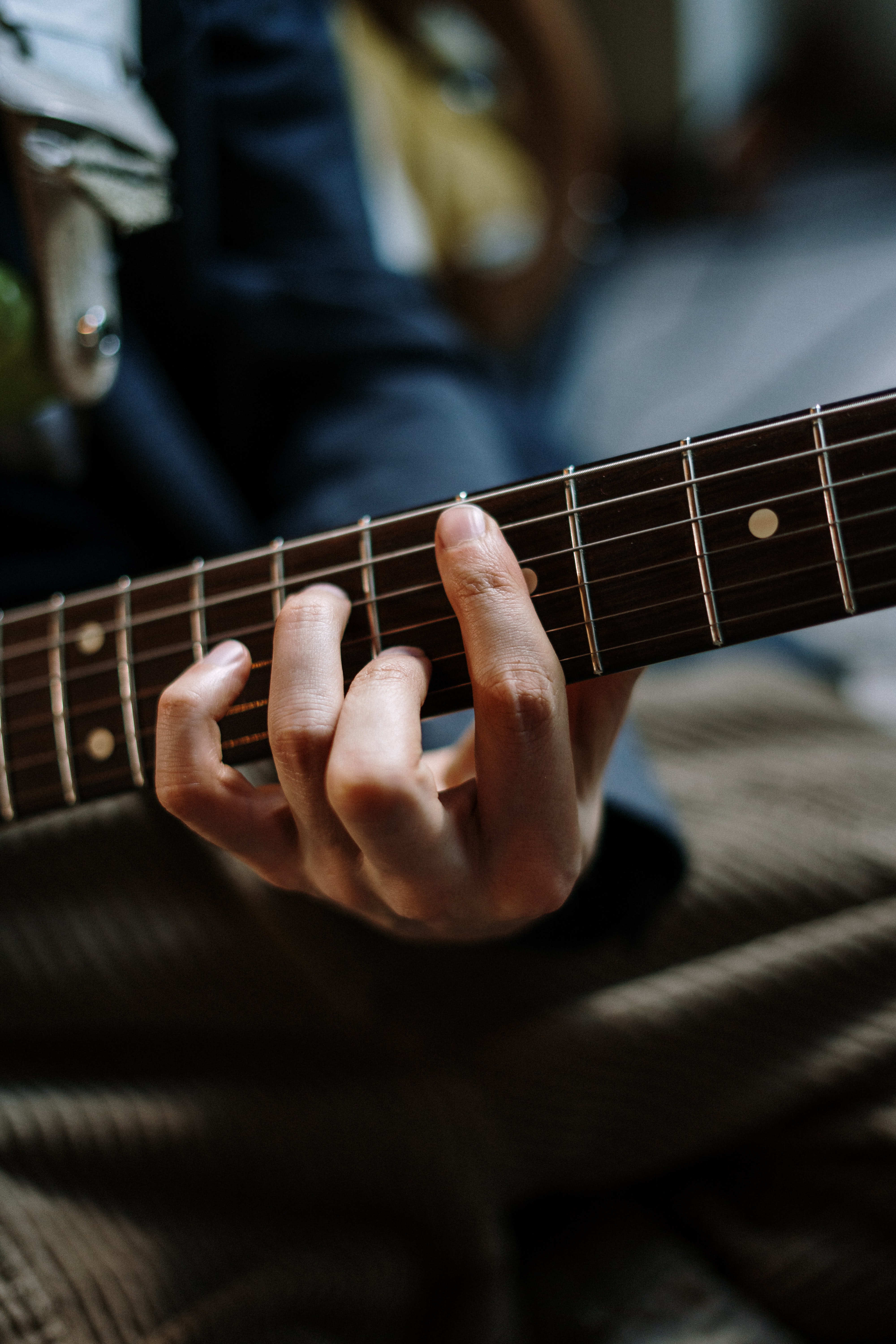 A close up of a person's hands playing a guitar. - Guitar