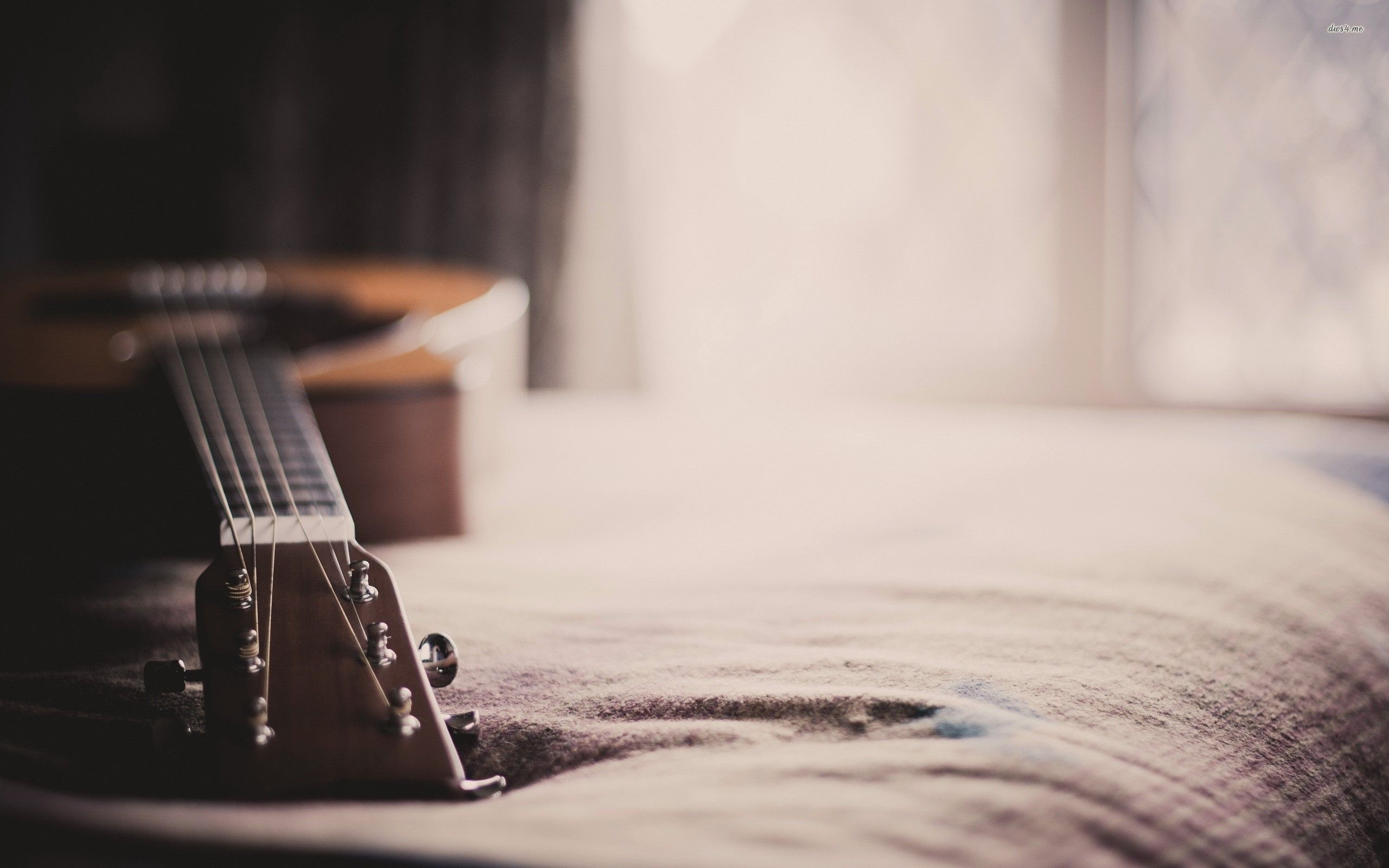A guitar sitting on top of bed - Guitar