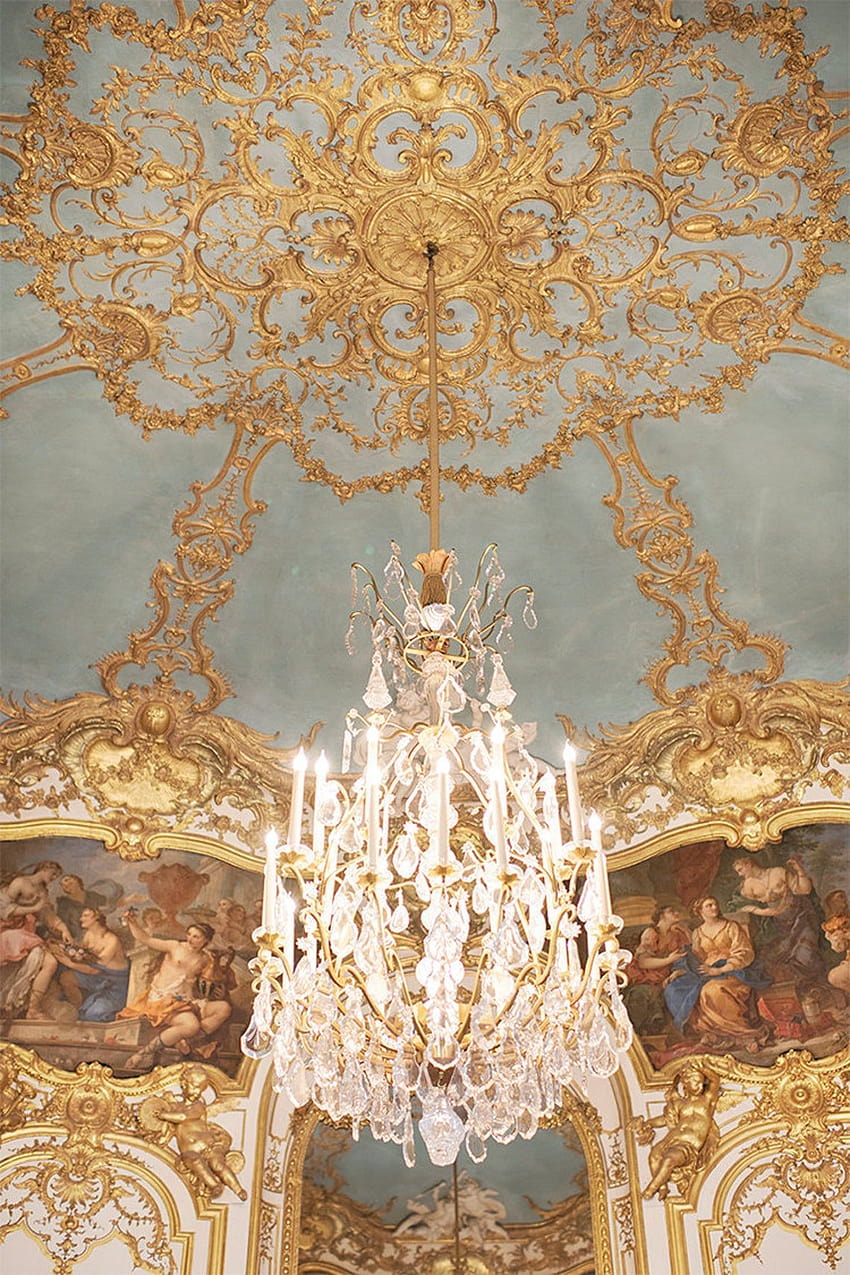 A chandelier hanging from the ceiling of an ornate room - Royalcore
