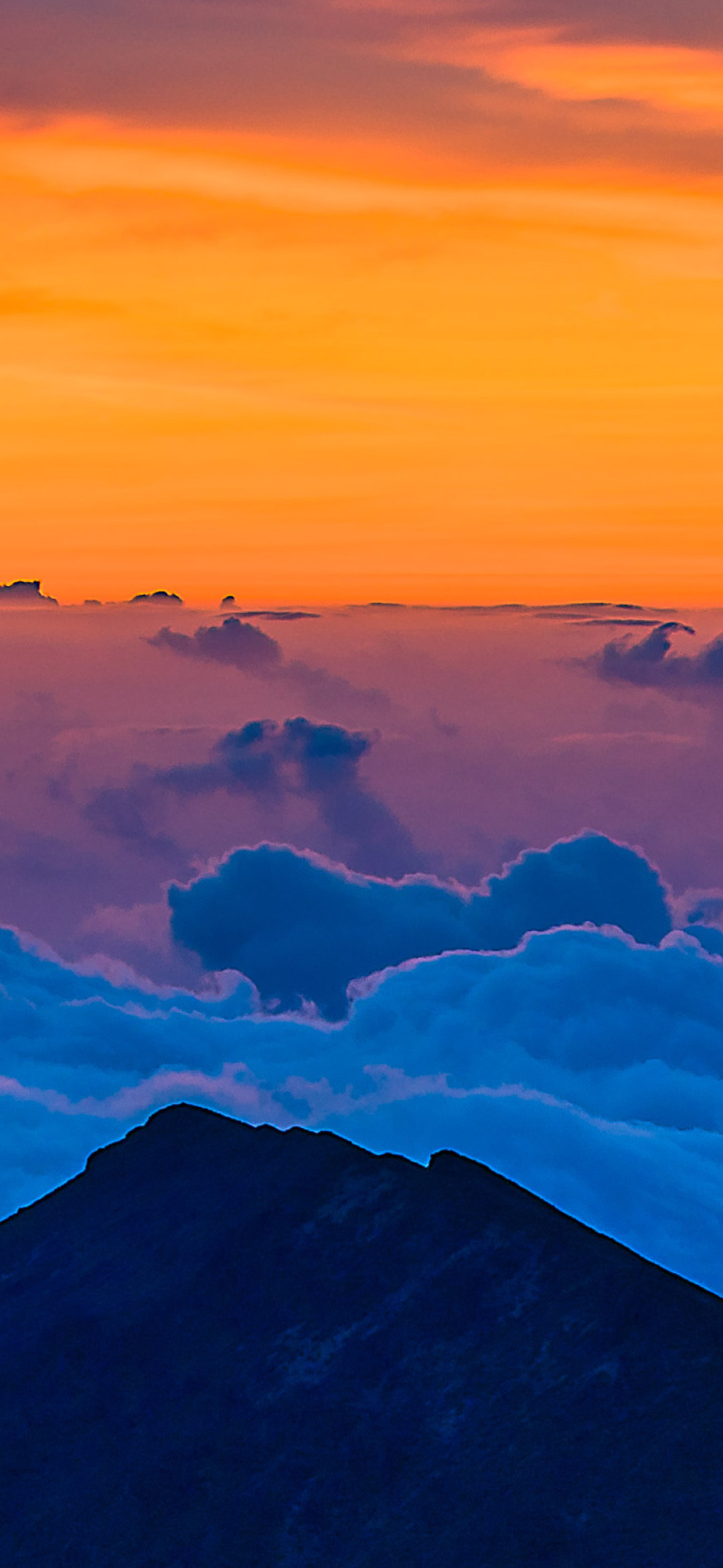 A mountain top with clouds and the sun setting - Hawaii, sunrise