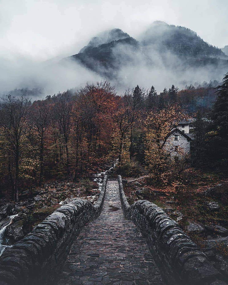 A stone bridge leads to a house in the mountains. - Fog