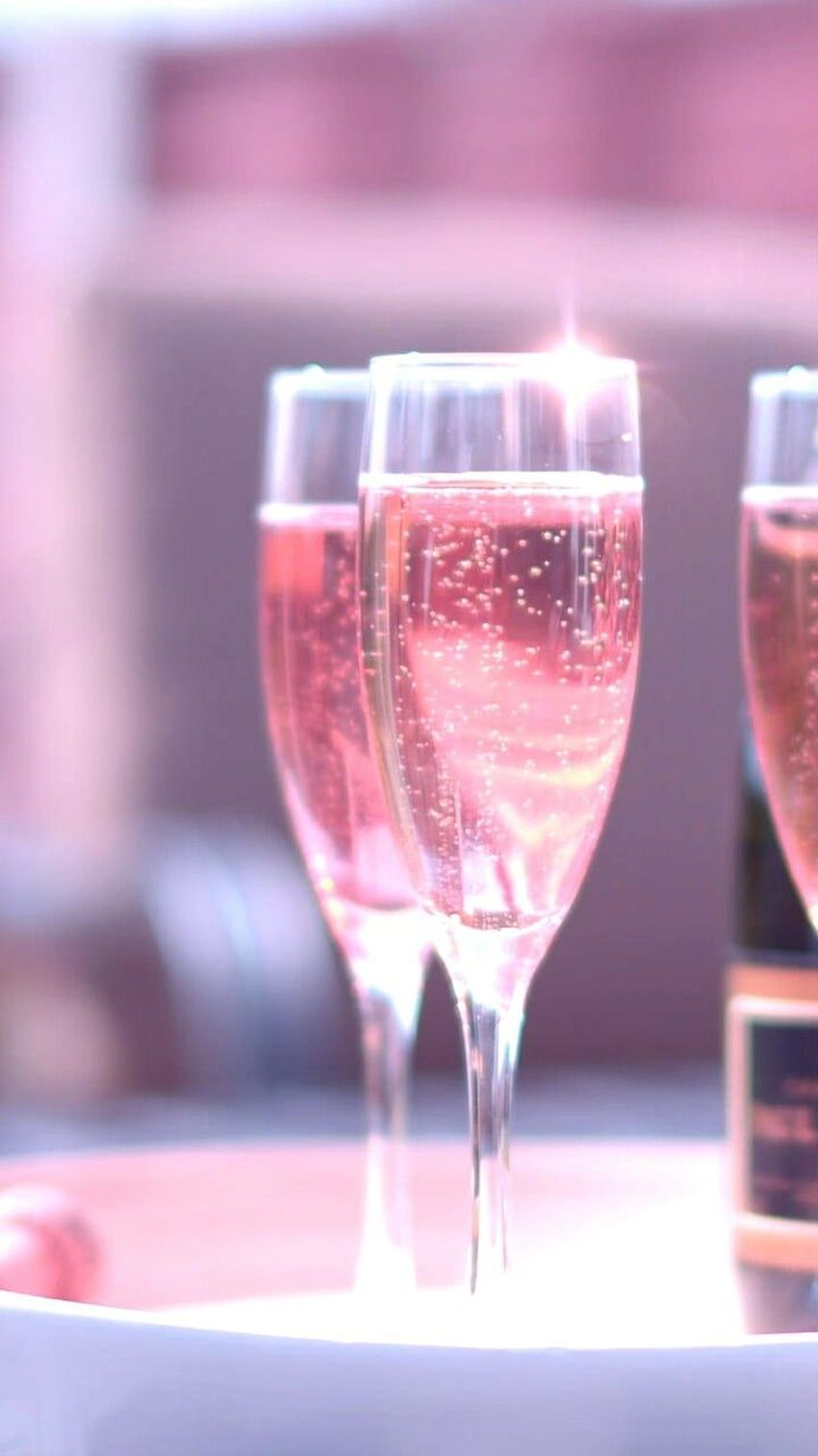 Two glasses of pink champagne sitting on a tray. - Champagne