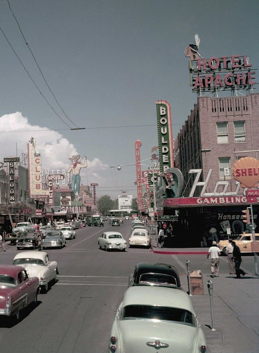 A busy street with neon signs and vintage cars. - Las Vegas