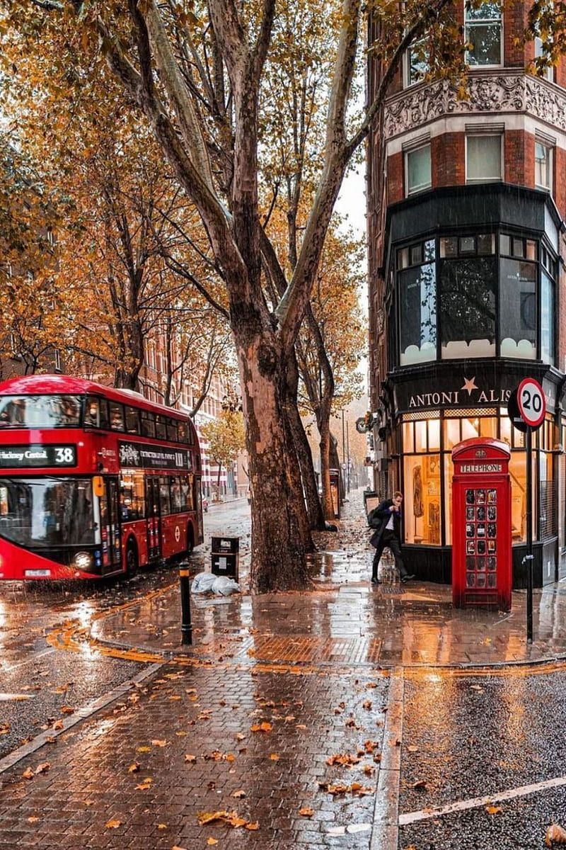 A red double decker bus driving down a rainy street - London