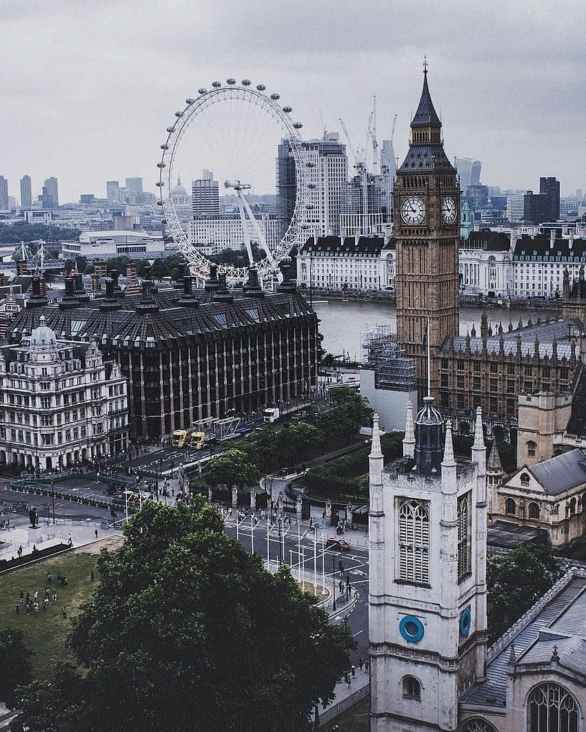 A city with a large clock tower and a giant ferris wheel. - London