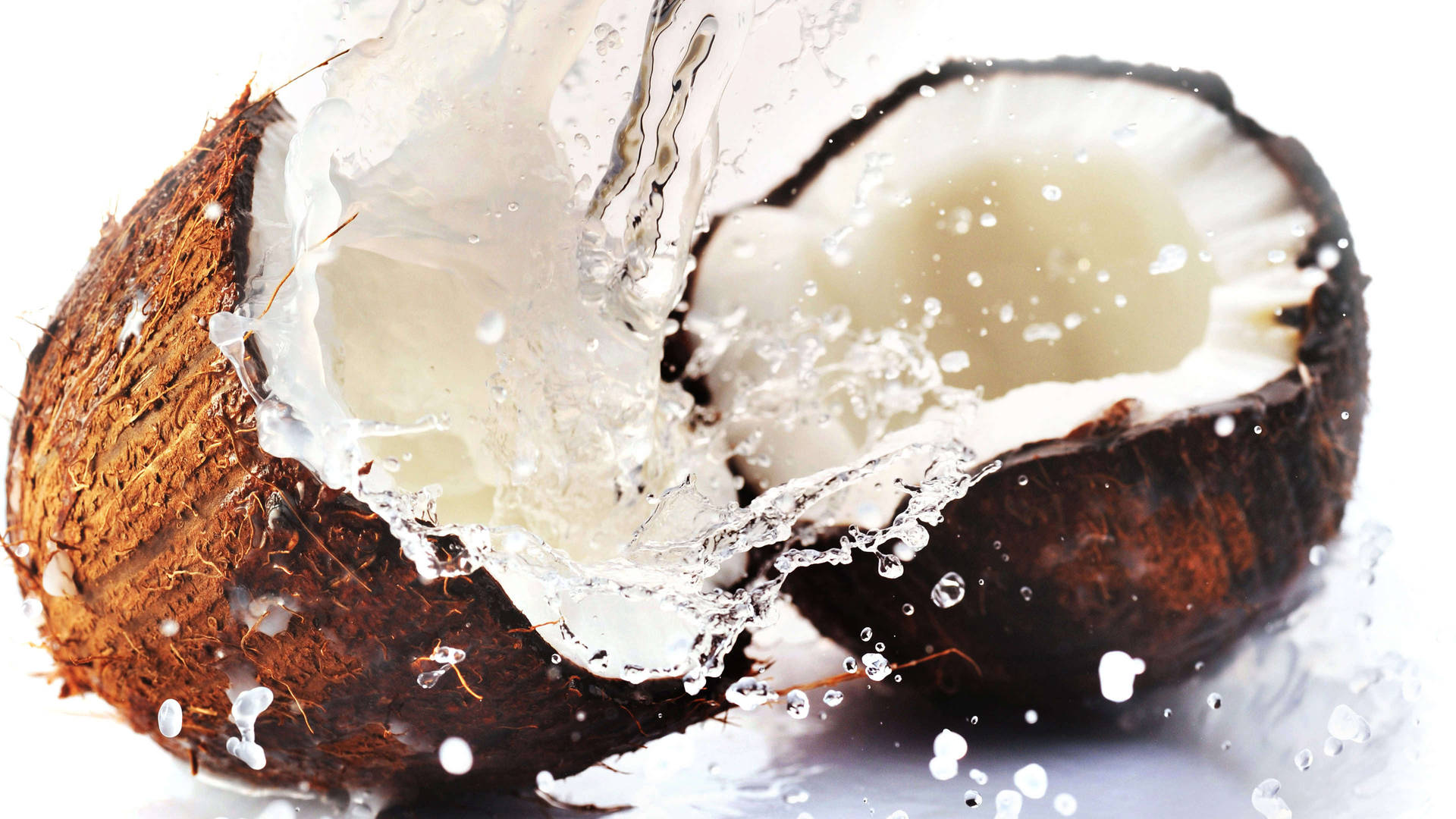 A coconut is being cut open and water splashes out - Coconut