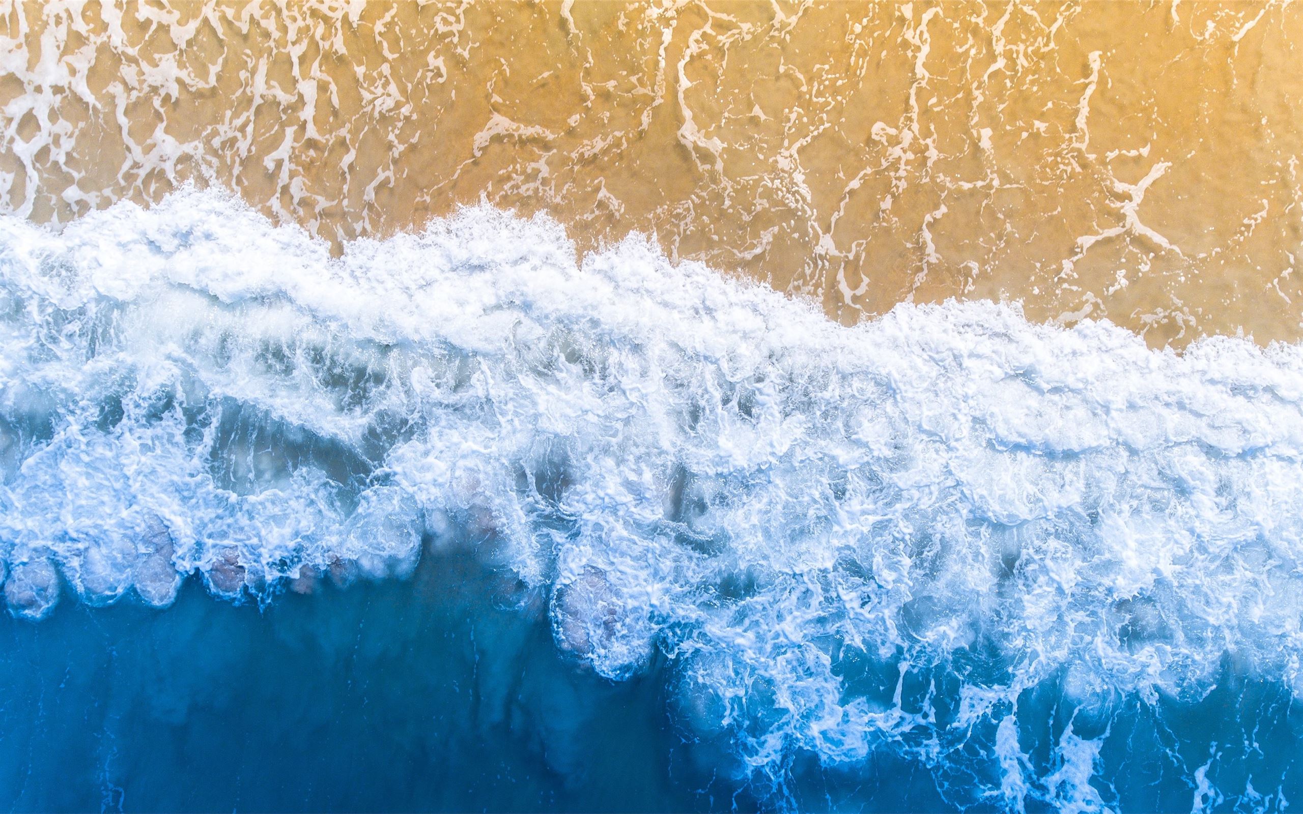 Aerial view of a wave breaking on a sandy beach - Surf