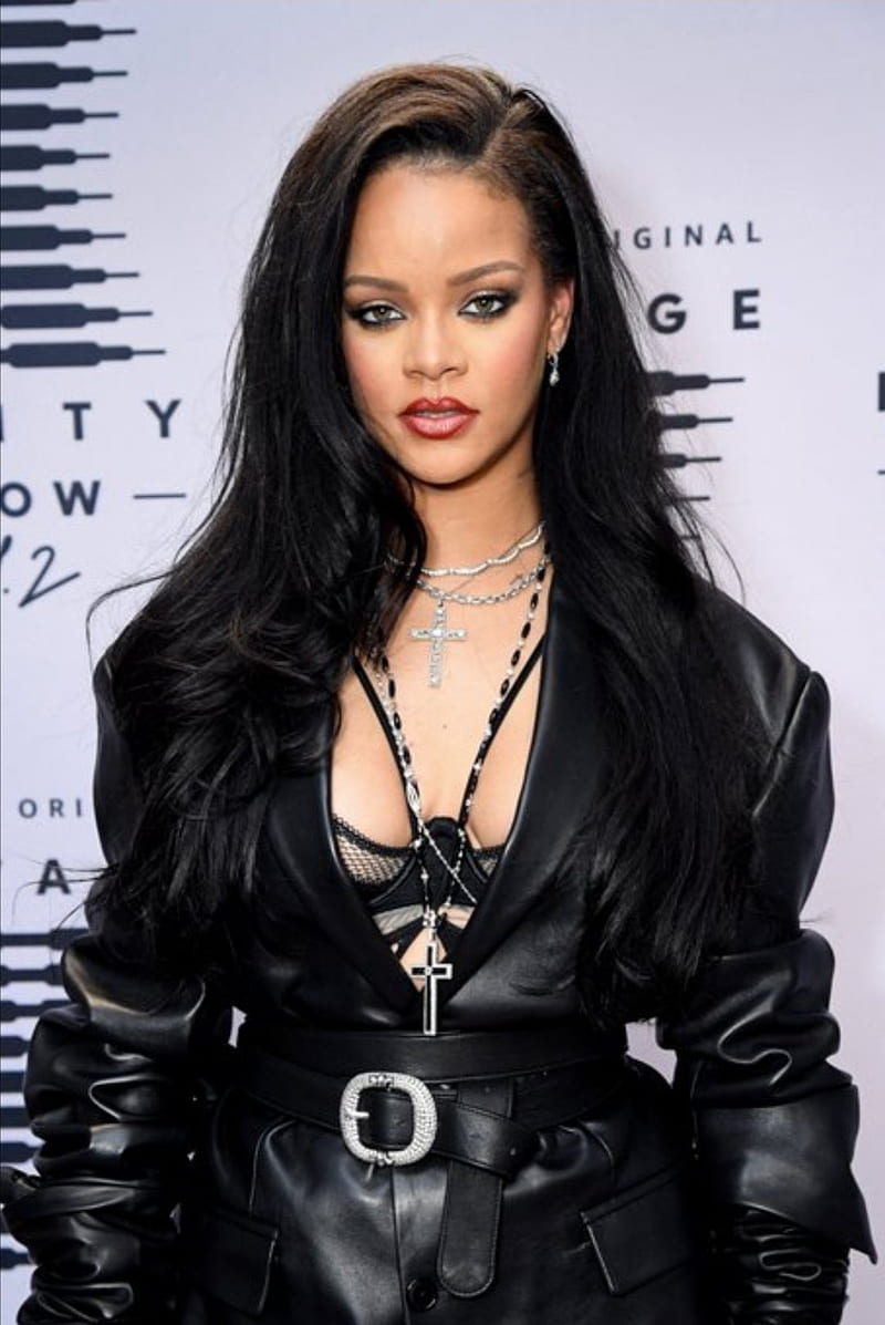 Rihanna at the Fenty Show, wearing a black leather jacket and a cross necklace. - Rihanna