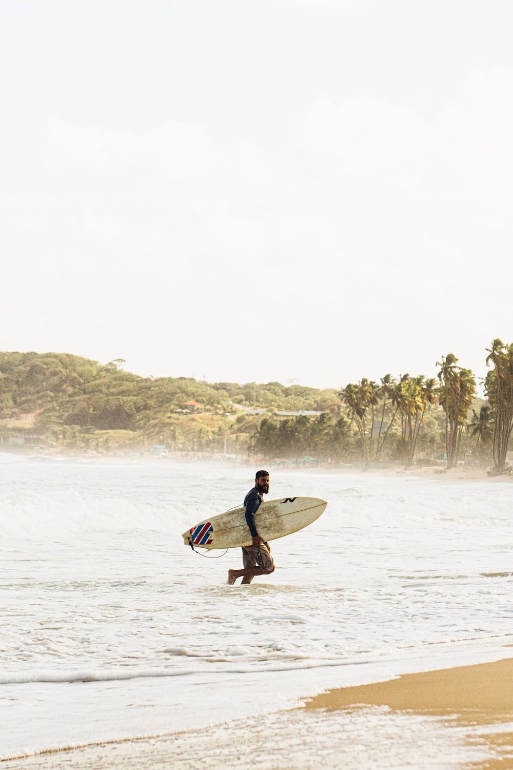 A man runs out of the ocean with a surfboard in hand. - Surf