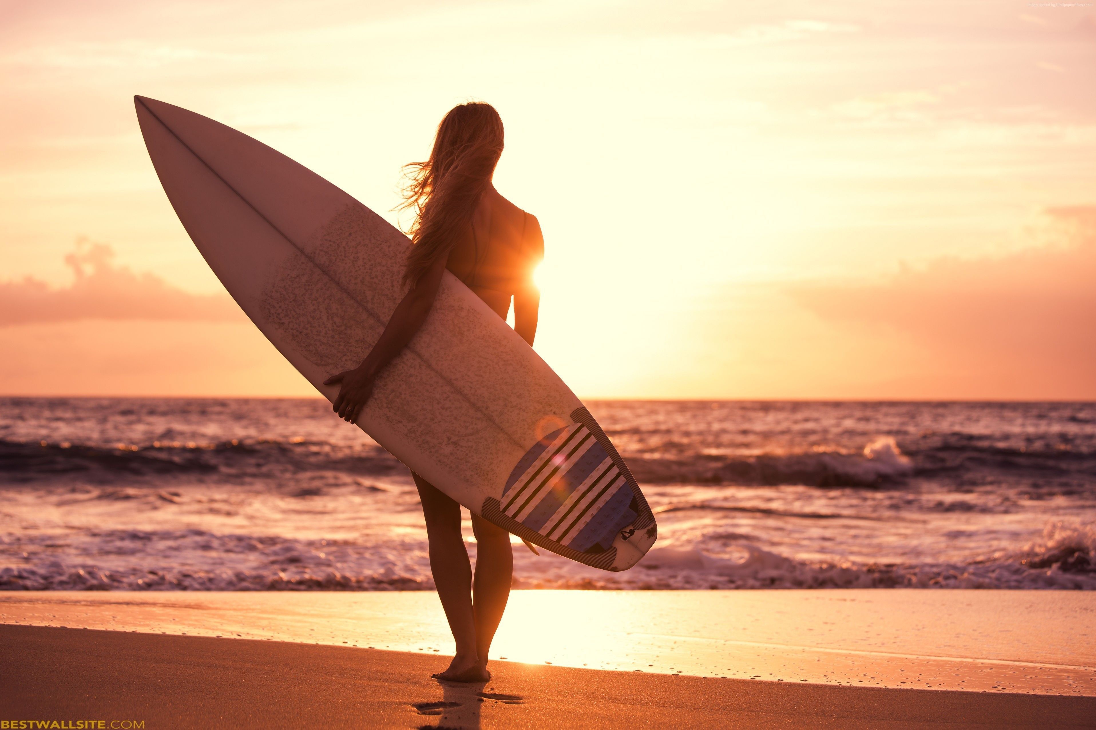 A woman with a surfboard watching the sunset - Surf