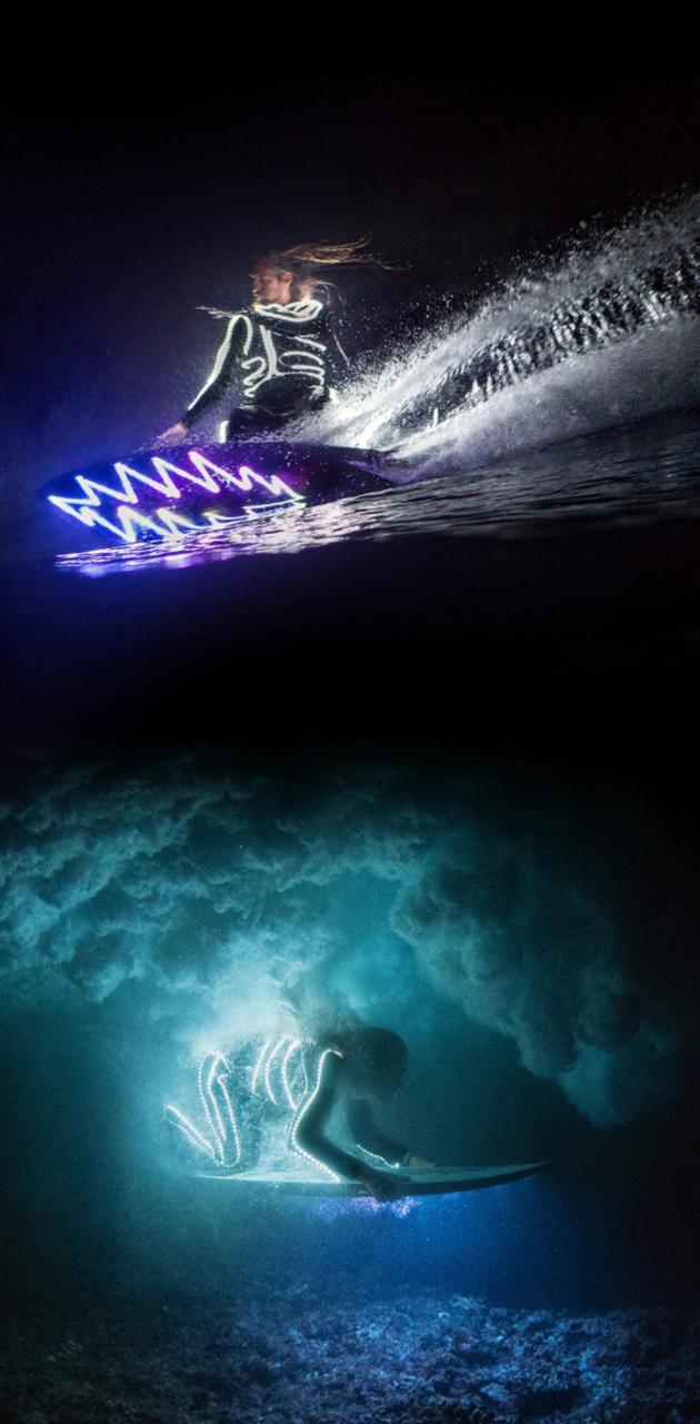 A man riding on top of water in the dark - Surf