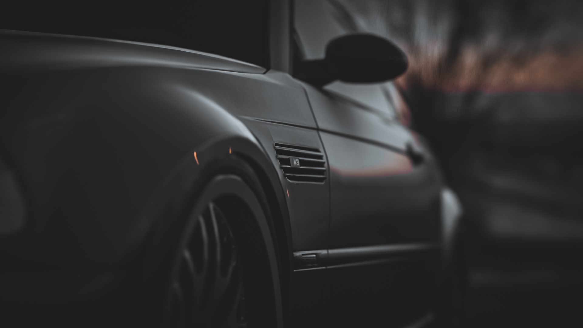 A close up of a black car with the wheel in the foreground - BMW