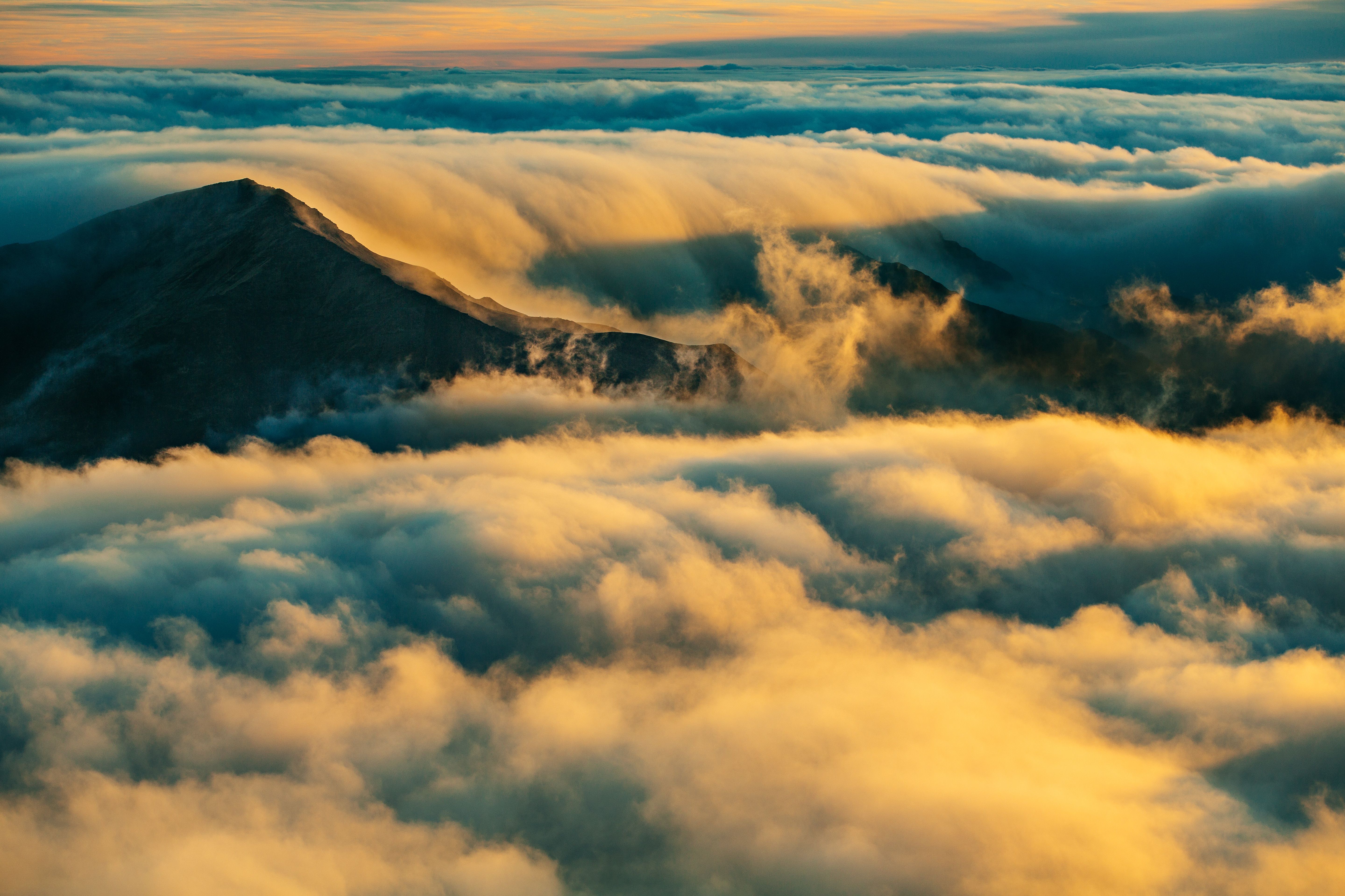 A mountain is surrounded by clouds and fog - Landscape