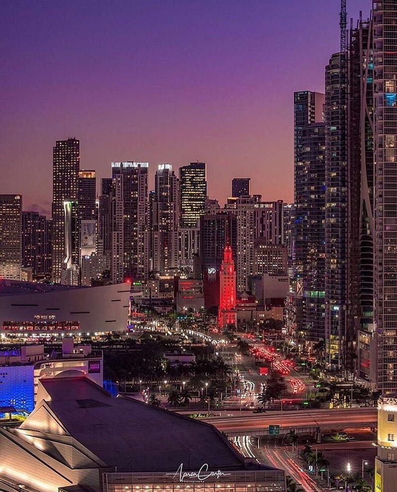 A city skyline at night with tall buildings lit up in red, white, and blue. - Miami, skyline