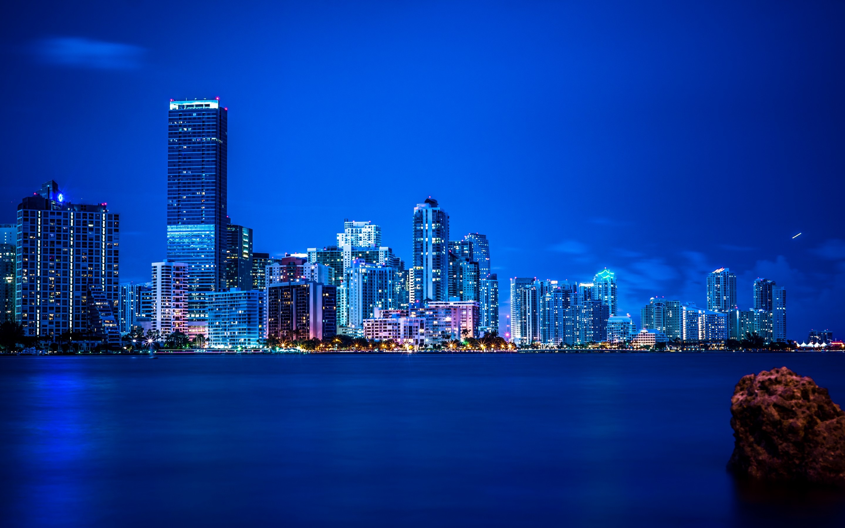 A skyline of buildings lit up at night. - Miami