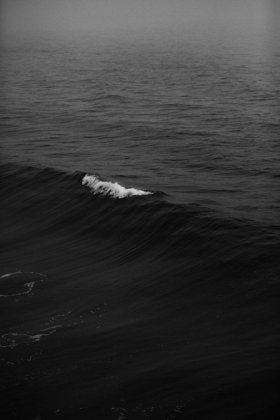 A black and white photo of a small wave in the ocean - Dark phone, dark
