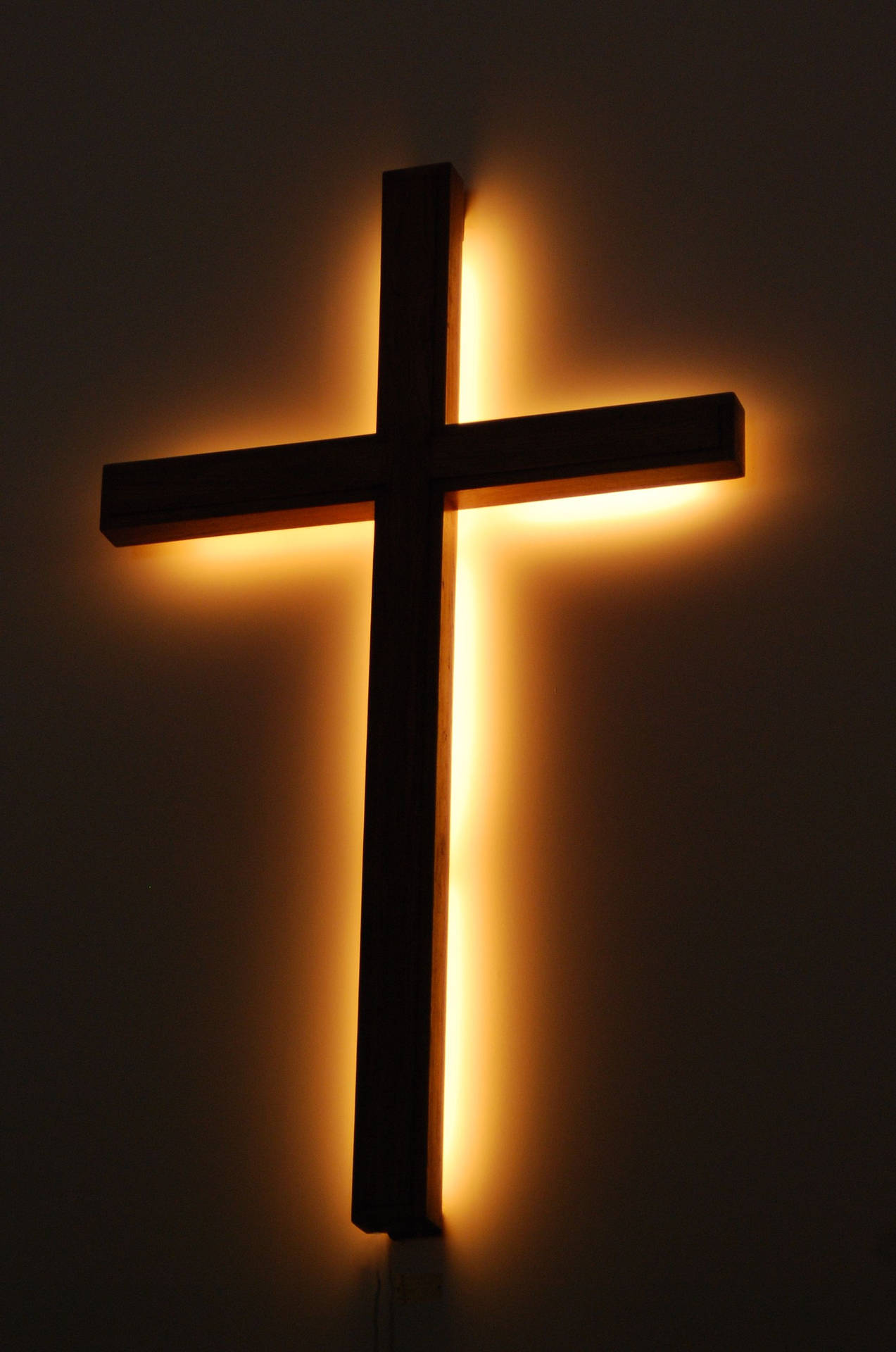 A wooden cross with a light behind it. - Cross