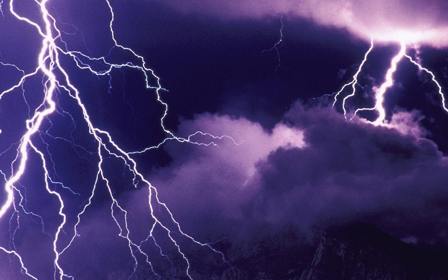 Lightning strikes in the sky over a mountain. - Lightning