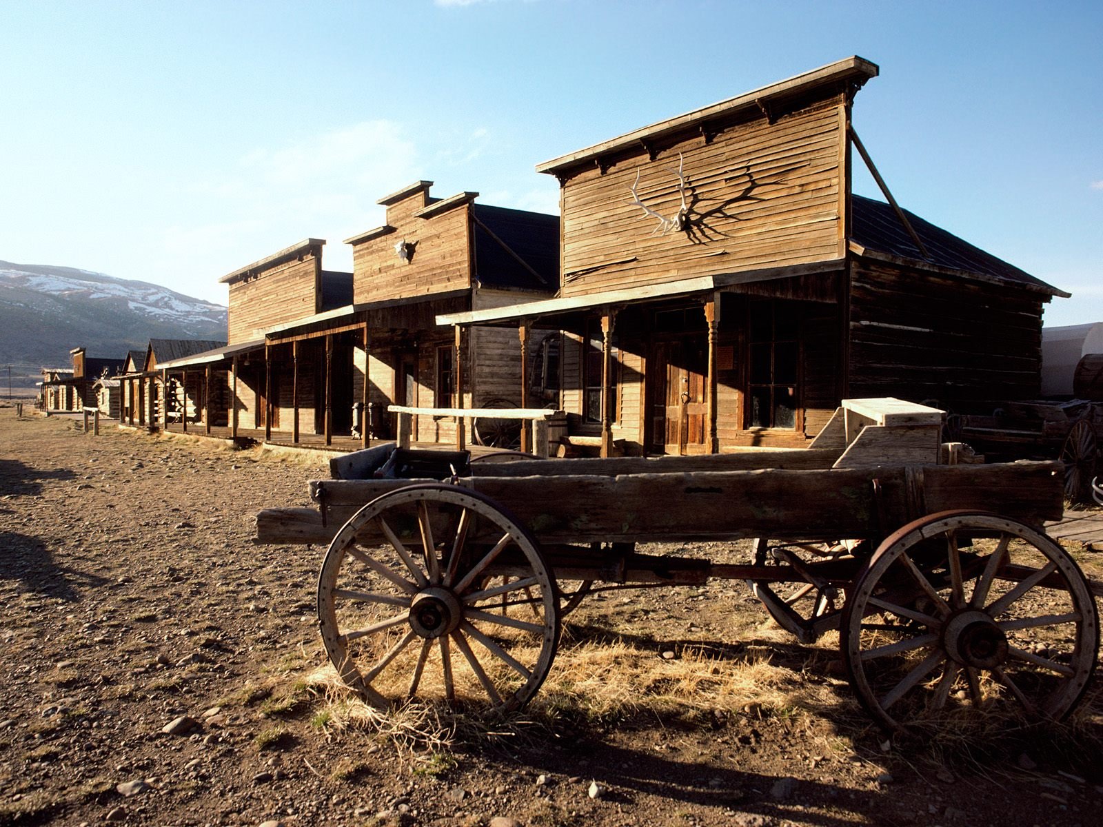 A wagon sitting in front of some old buildings - Western