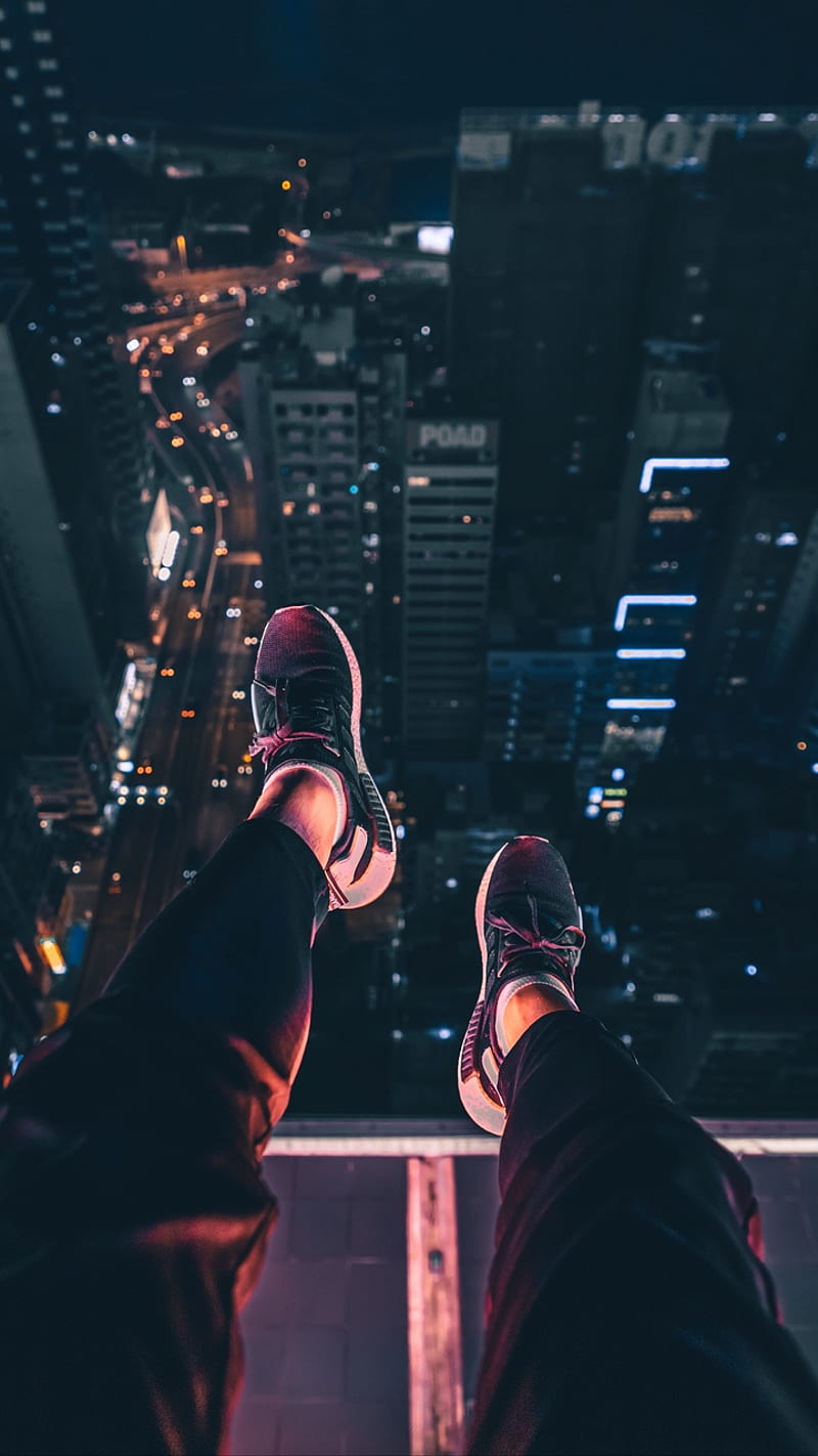 A person standing on the edge of building - Shoes