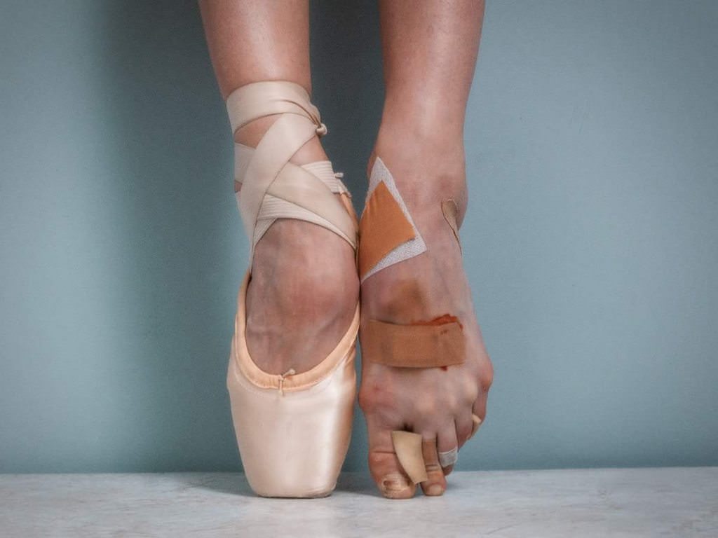 A woman's feet in pointe shoes with bandages on her toes - Ballet