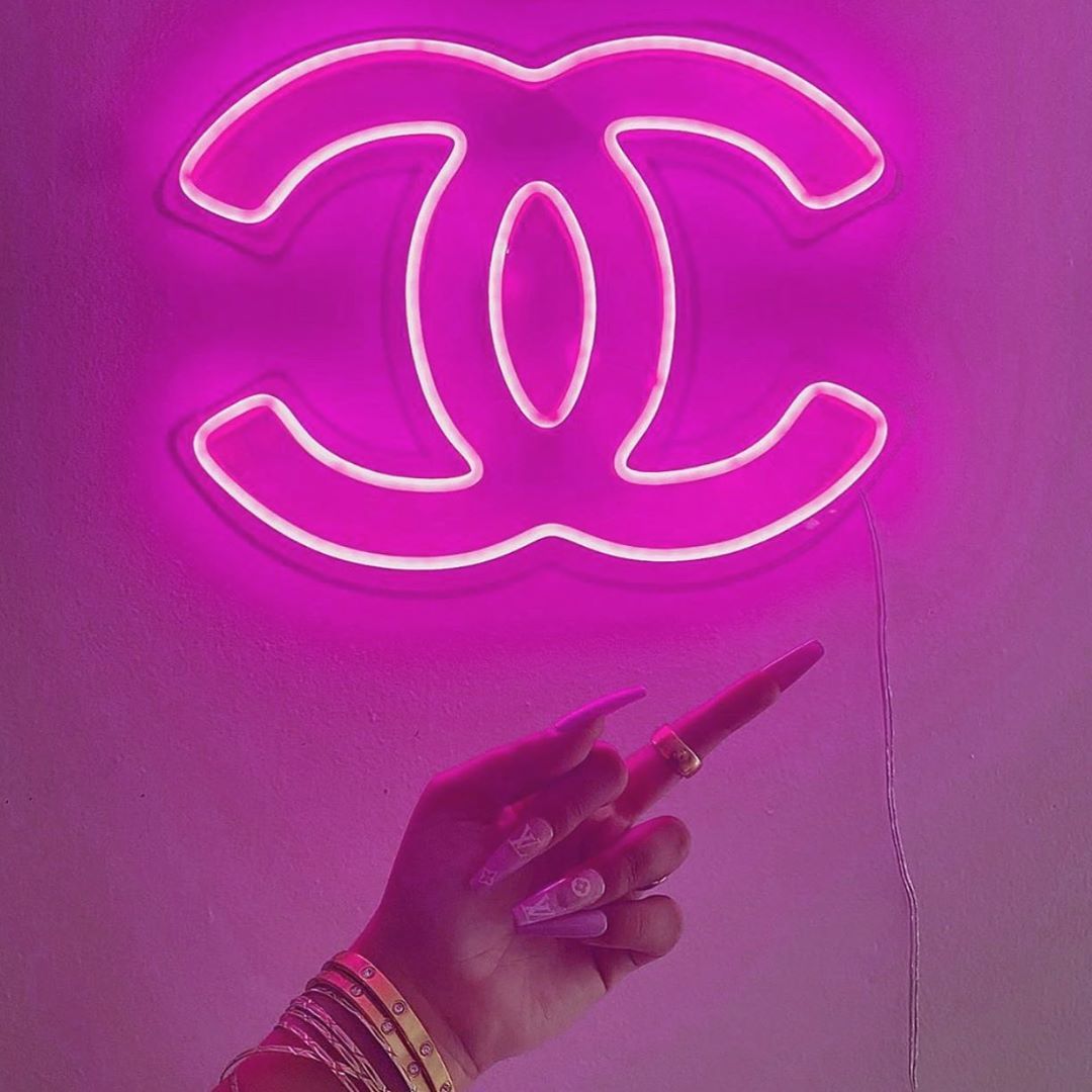 A person holding up an illuminated chanel sign - Nails