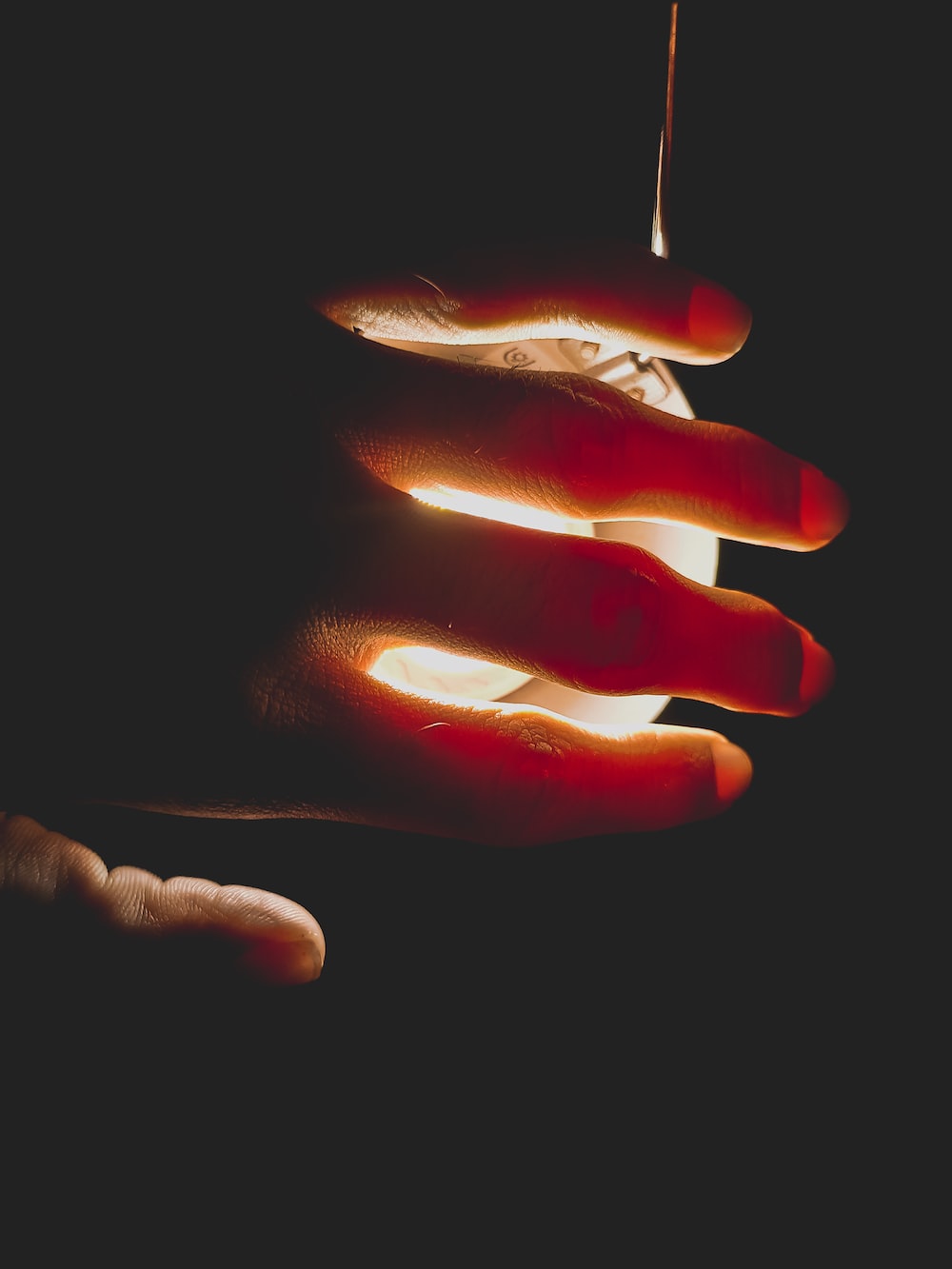 A hand holding an object with light coming from it - Nails