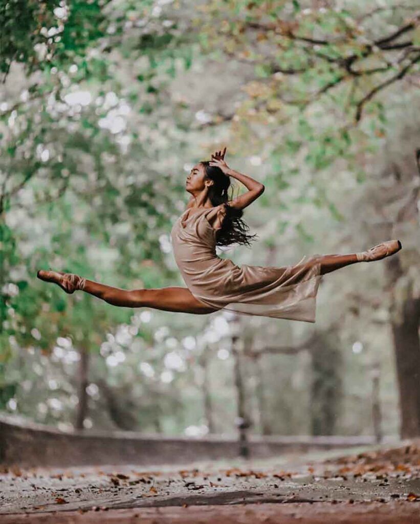 A woman in the middle of jumping through trees - Ballet