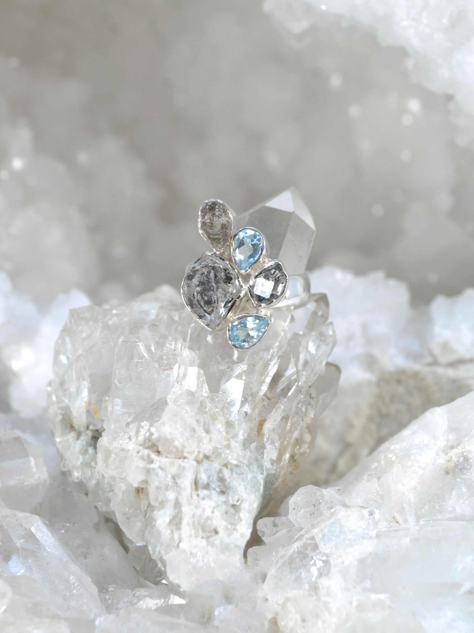 A silver ring with a cluster of herkimer diamonds and blue topaz on top of a crystal - Diamond