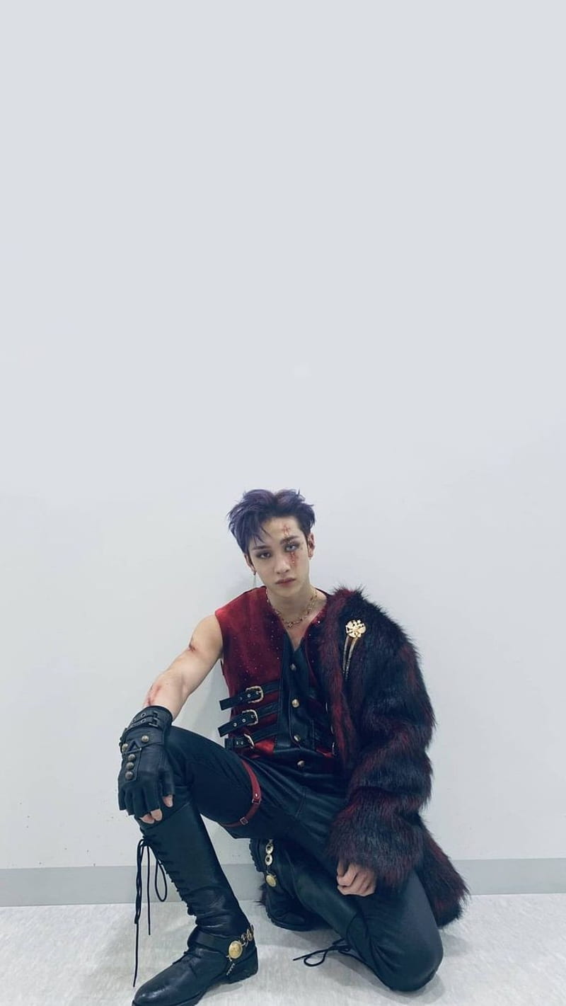 A man in black and red clothing sitting on the floor - Bang Chan