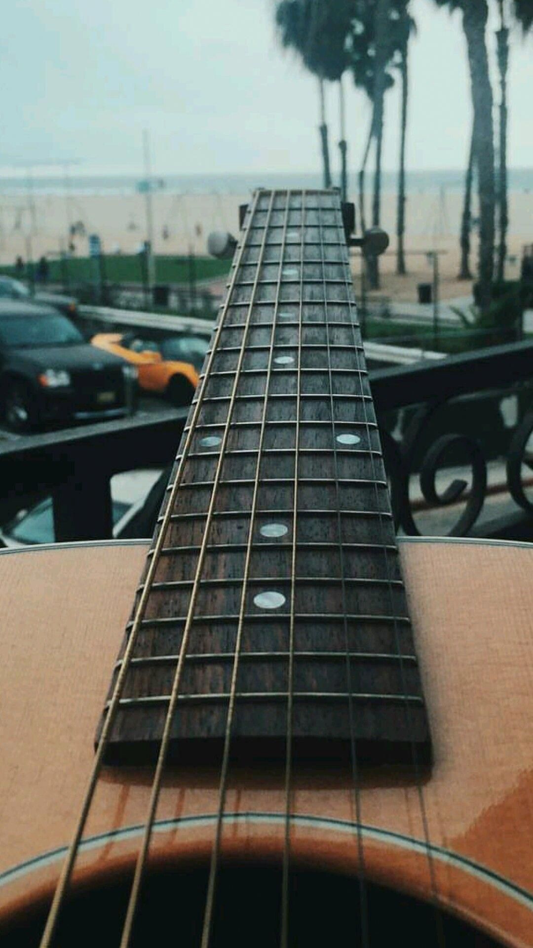 A guitar neck is on the side of an outdoor patio - Guitar
