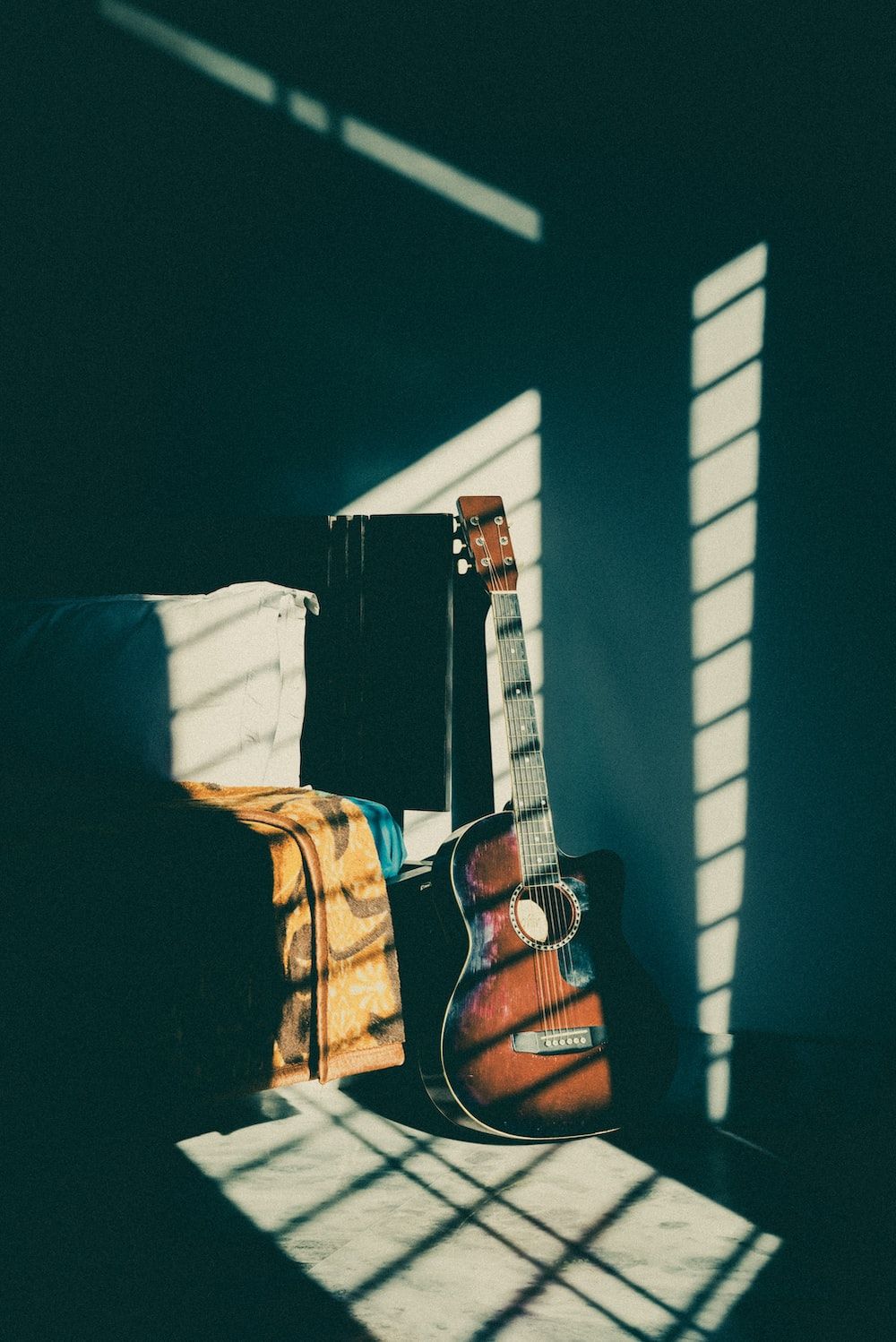 brown acoustic guitar on black and white striped textile photo