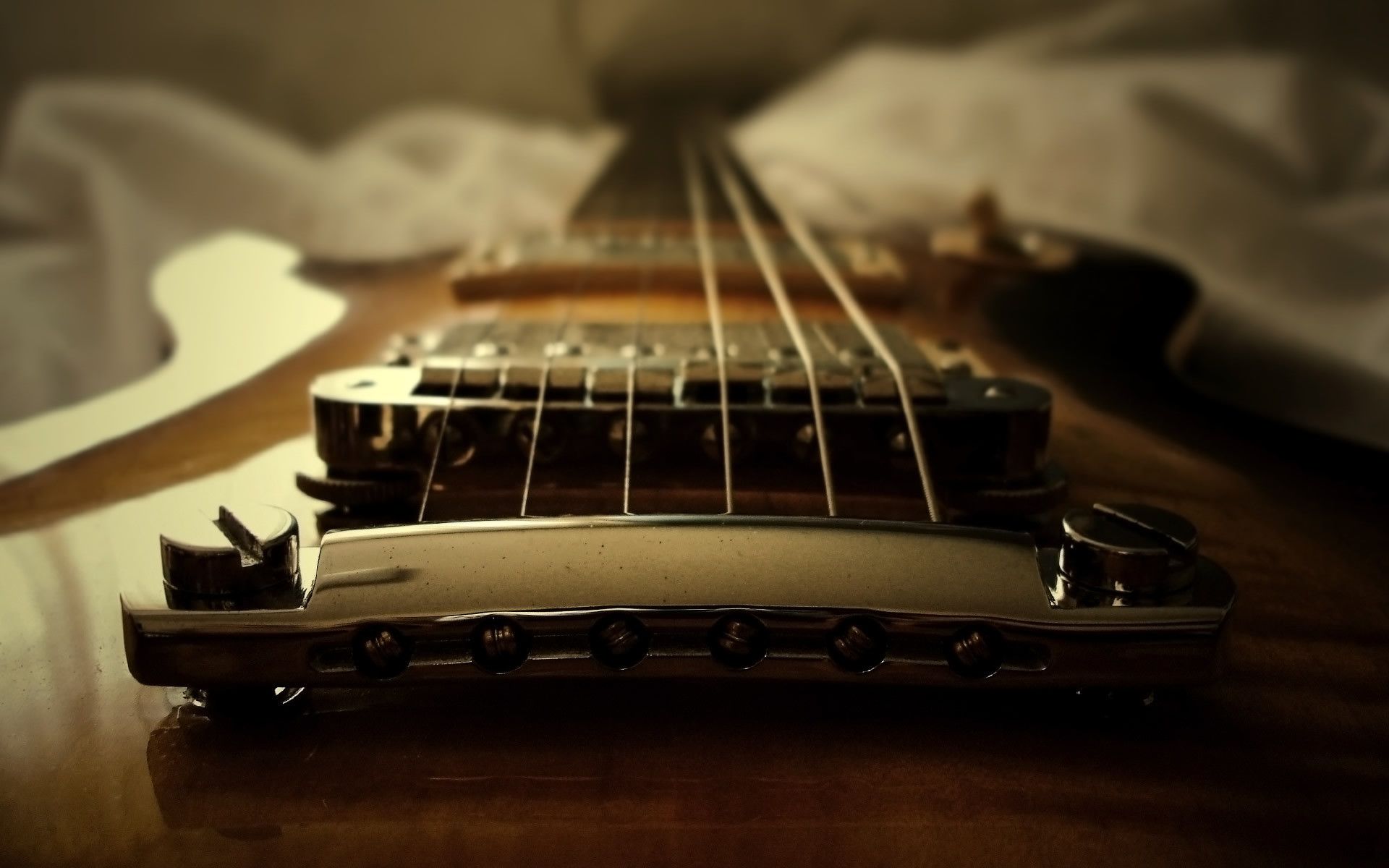 A guitar is laying on top of white sheets - Guitar