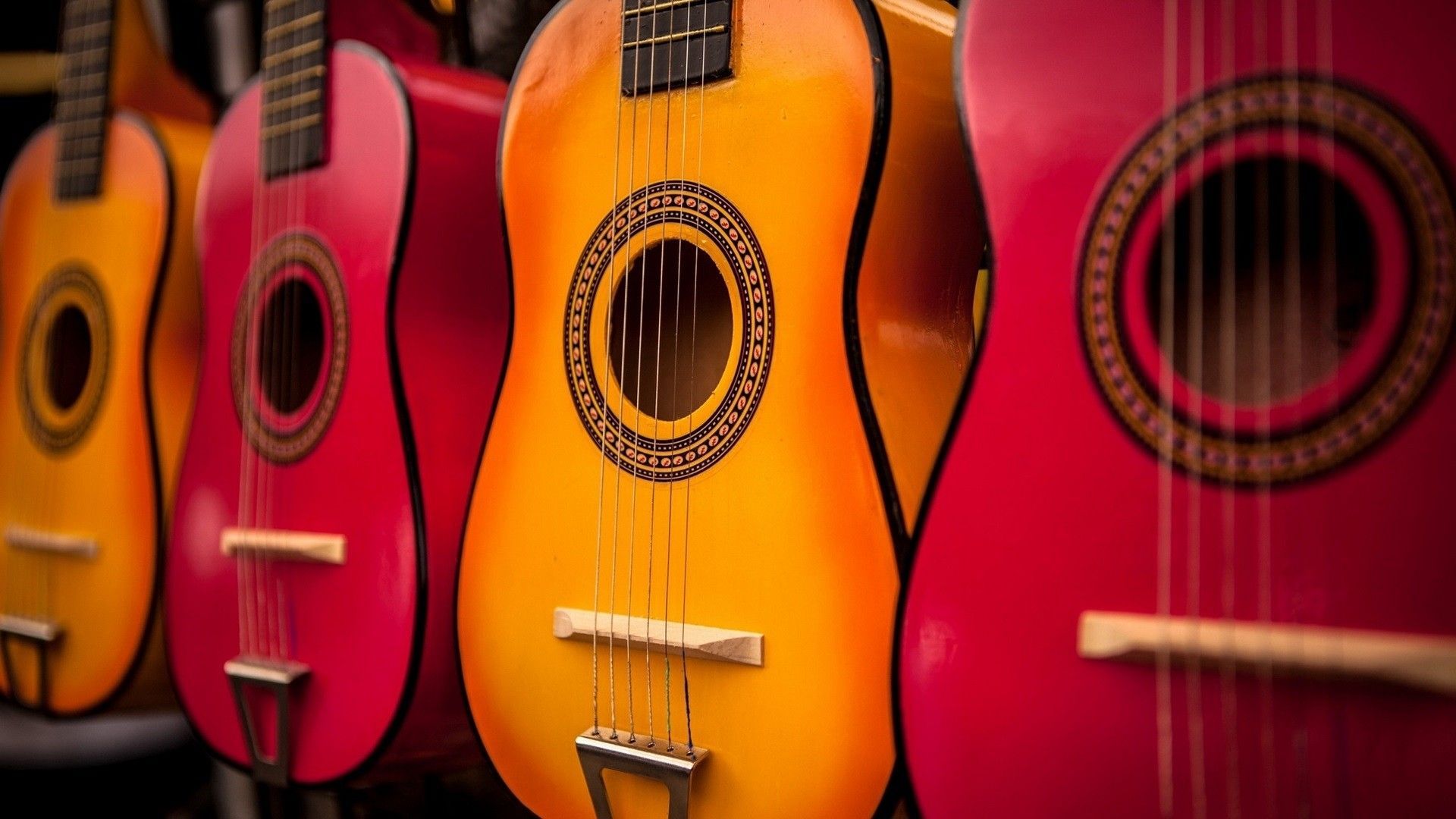 A row of guitars, including a red one with a circular design on the body. - Guitar