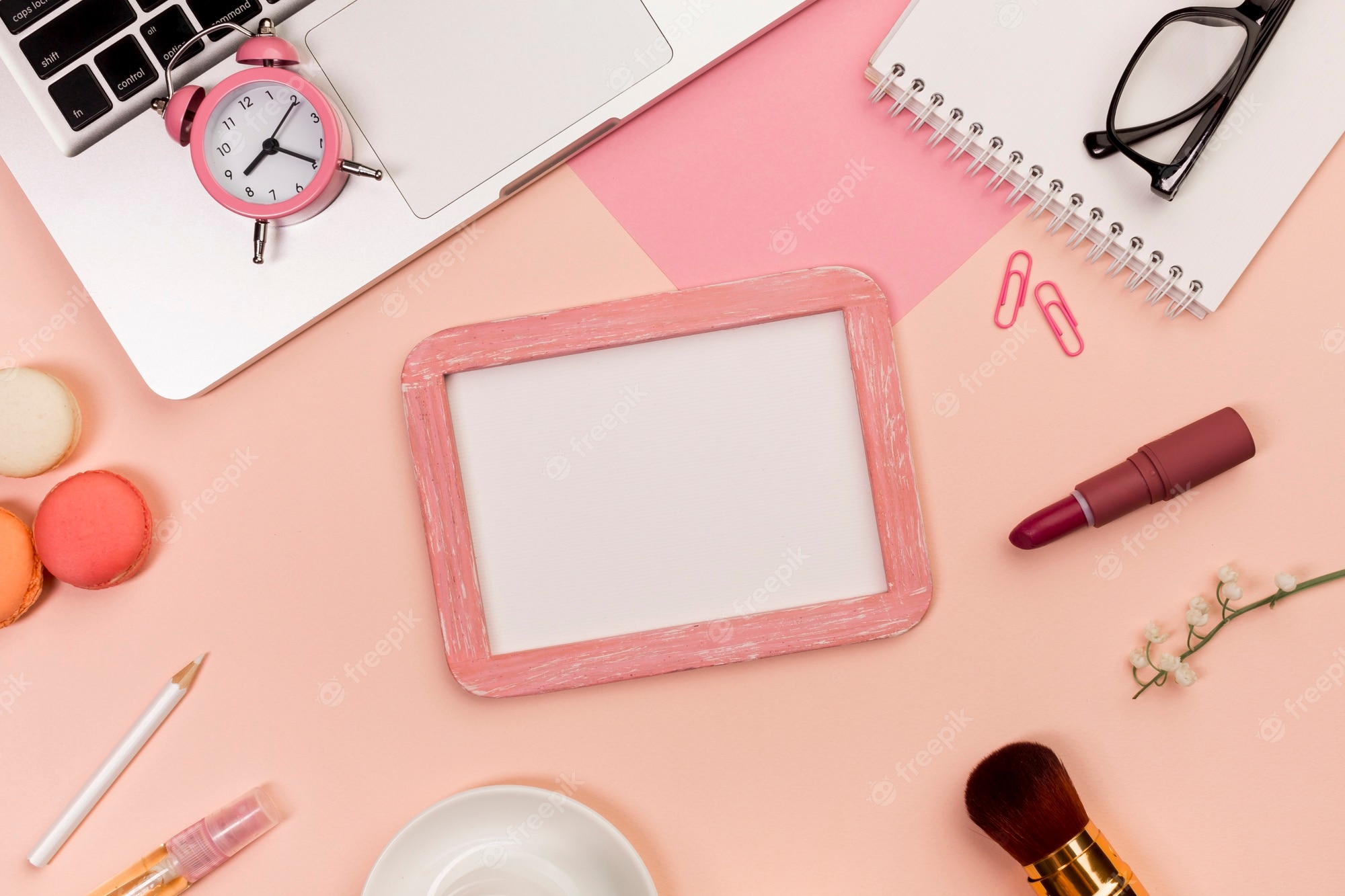 Free Photo. Alarm clock on laptop with makeup brush, macaroons, whiteboard slate on colored background