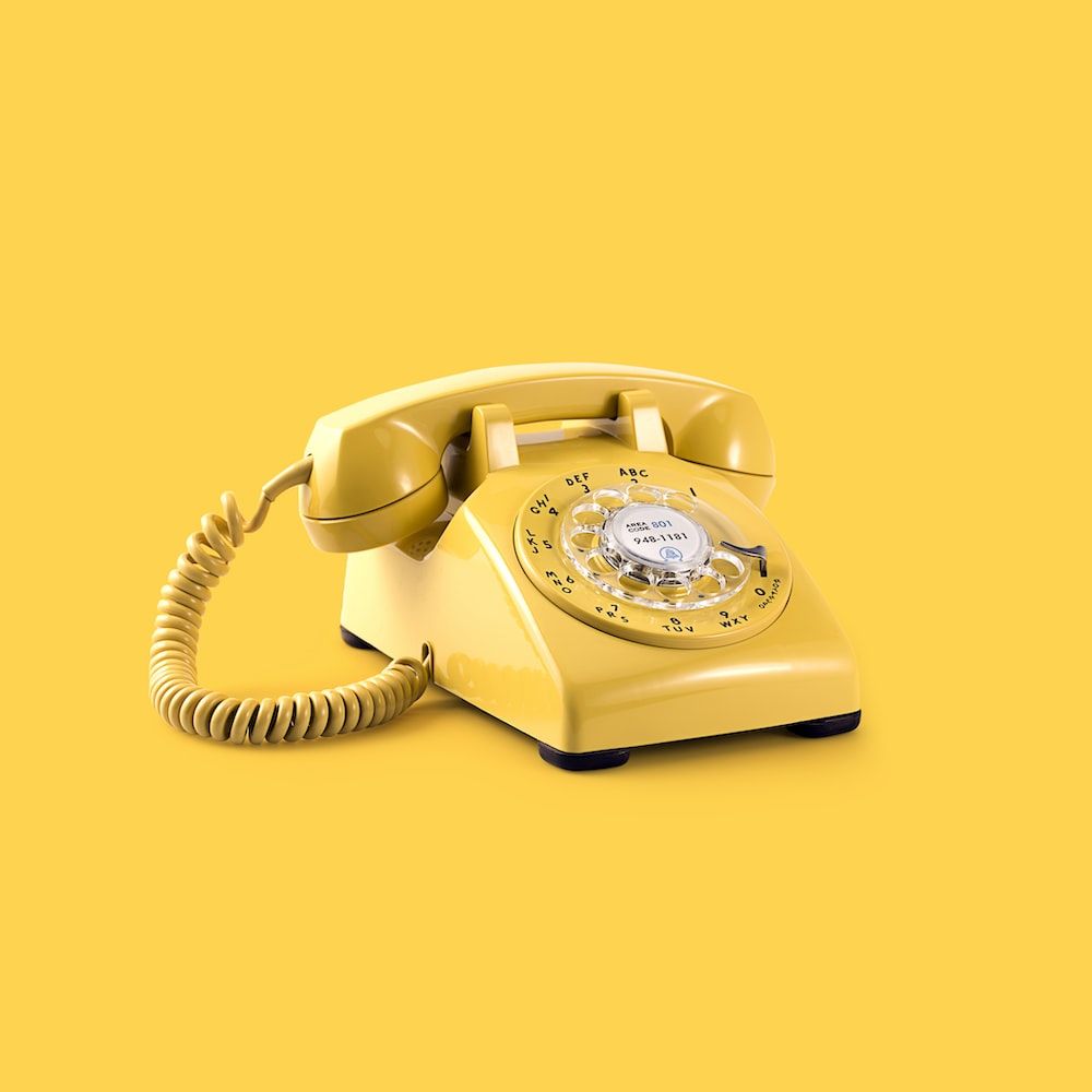 A yellow rotary phone on a yellow background - Light yellow