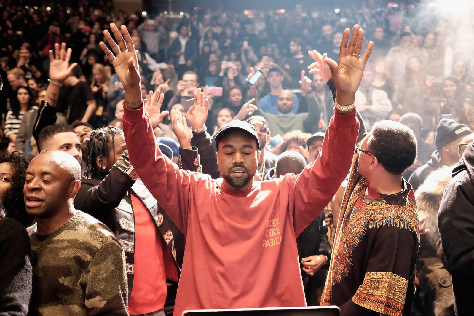 A man in red shirt is standing on stage - Kanye West