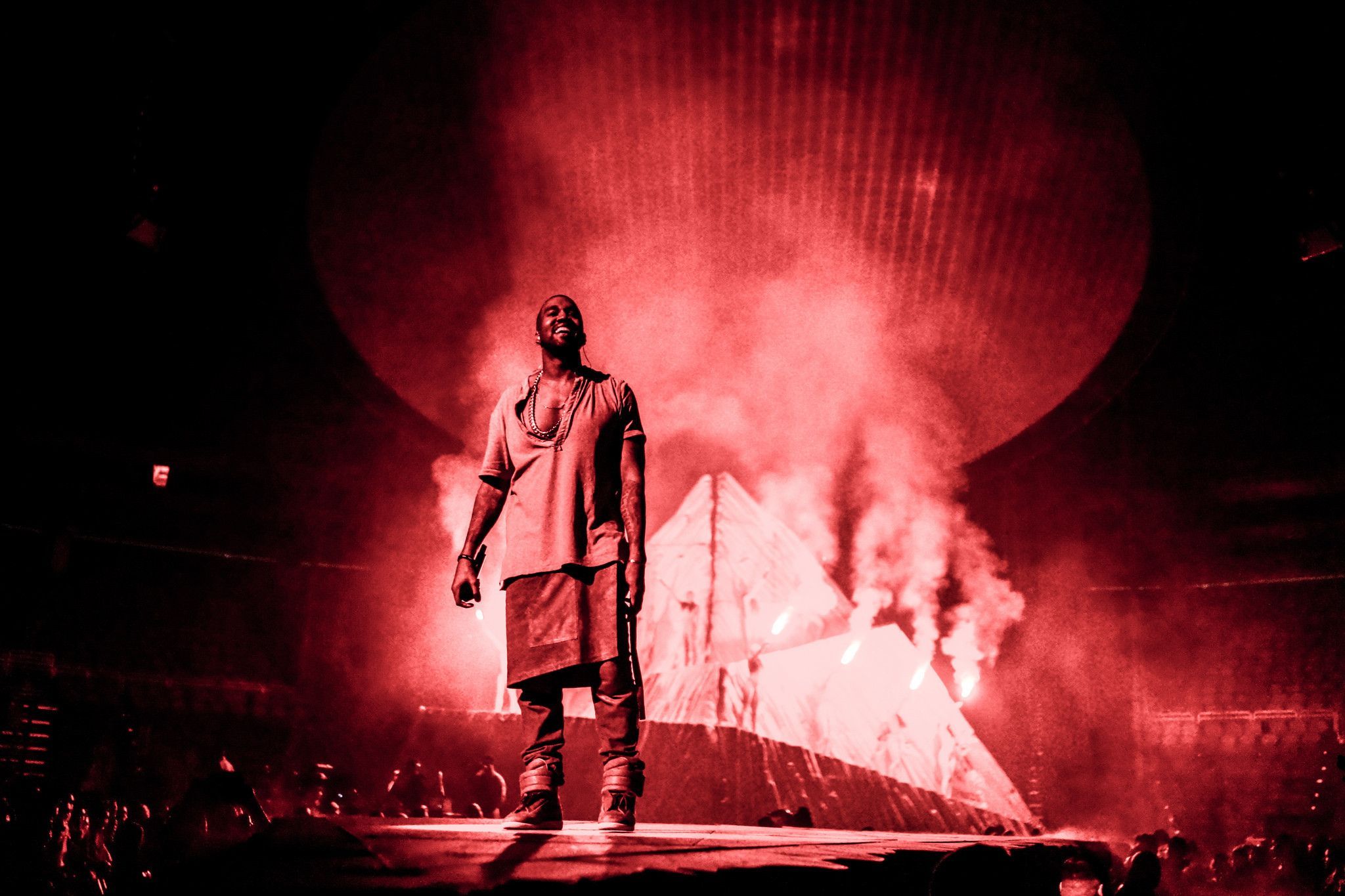 A man standing on stage in front of flames - Kanye West