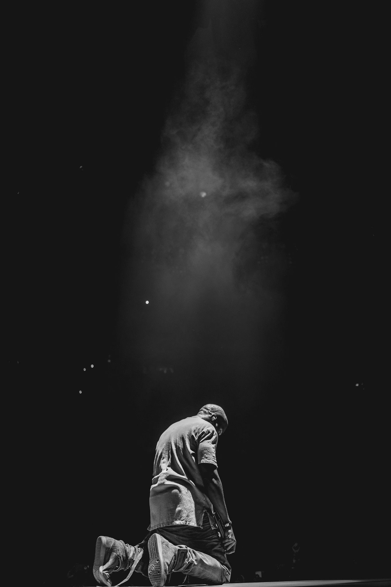 A man kneeling on the ground in front of his shoes - Kanye West