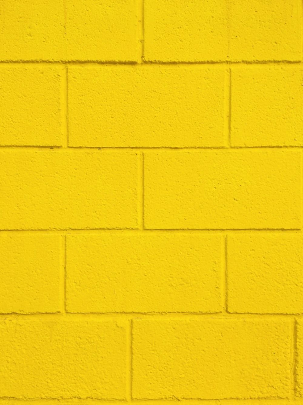 A yellow brick wall with some bricks missing - Light yellow, pastel yellow