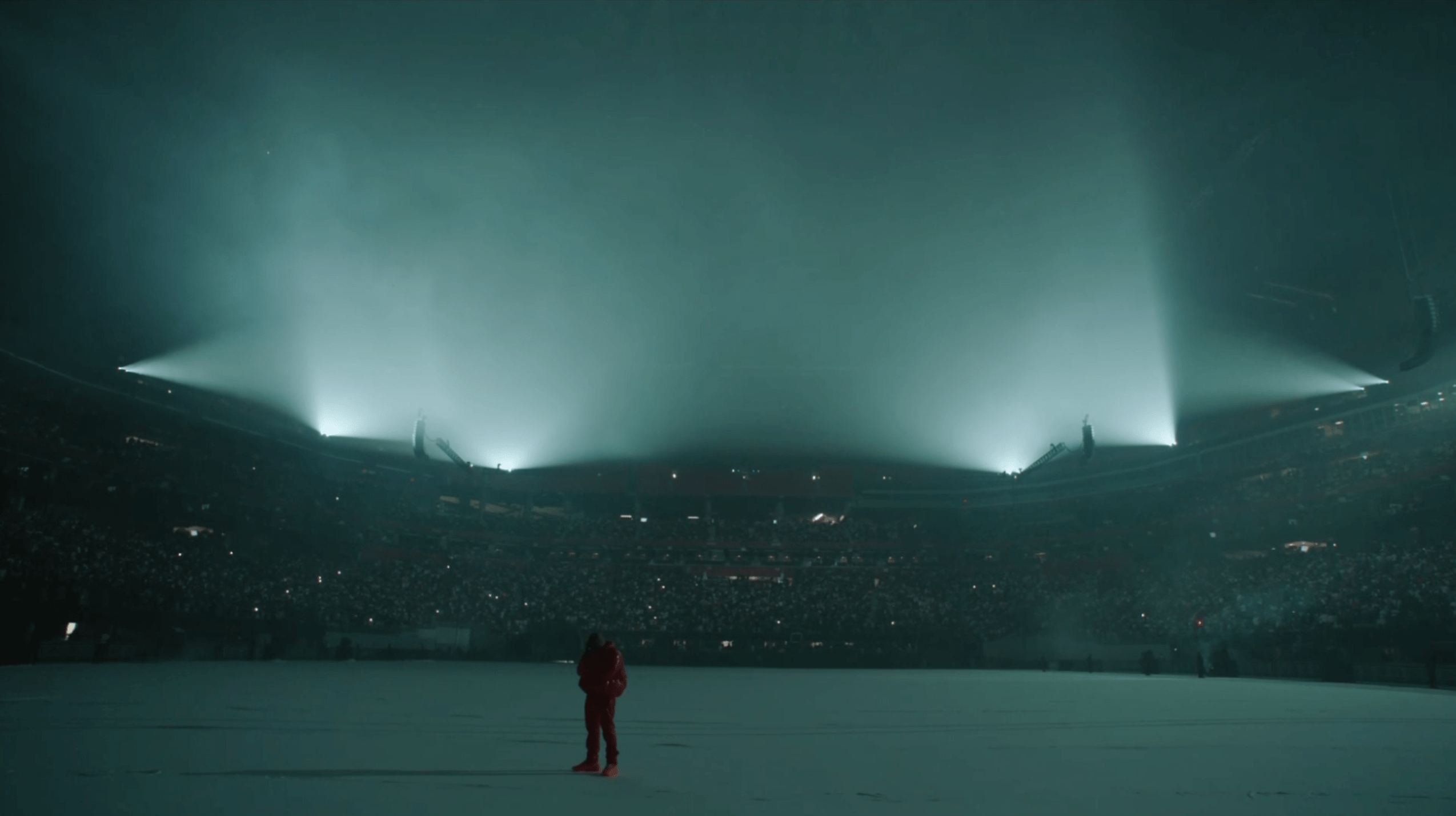 A person standing in a stadium with lights shining down on them - Kanye West