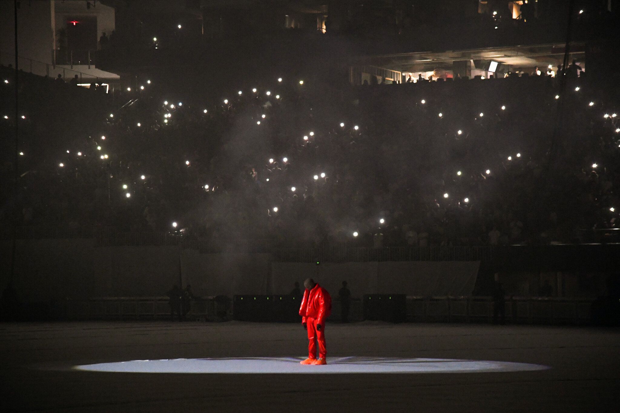 A man in an orange suit is standing on the ice - Kanye West